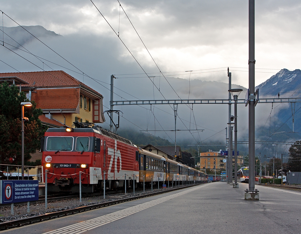 Die HGe 4/4 101 963-7 der zb (Zentralbahn) �bernimmt am 29.09.2012, morgens in Meiringen nun den RegioExpress GoldenPass Panoramic. 
Den der zahnlose Gep�cktriebwagen De 110 021-3 (ex De 4/4 121, ex Deh 4/6 905) von Interlaken Ost nach hier gezogen hat. 
Grund ist von Meiringen geht es teilweise mit Zahnstange (System Riggenbach) �ber den Br�nigpass (bis zu 13 %) und die HGe 4/4 101 ist eine schmalspurige gemischte Zahnrad- und Adh�sions-Lokomotive, und da Meiringen ein Kopfbahnhof ist, ergibt sich auch kein grosser Mehraufwand durch den Lokwechsel. 
Techn.Daten der HGe 4/4 101: 
Die Dauerleistung betr�gt 1.875 kW, die H�chstgeschwindigkeit betr�gt bei Adh�sion 100 km/h mit Zahnrad 40 km/h, das Zahnradsystem ist Riggenbach, die Lok wiegt 63 t und hat eine L�nge von 14,8 m �ber Puffer.