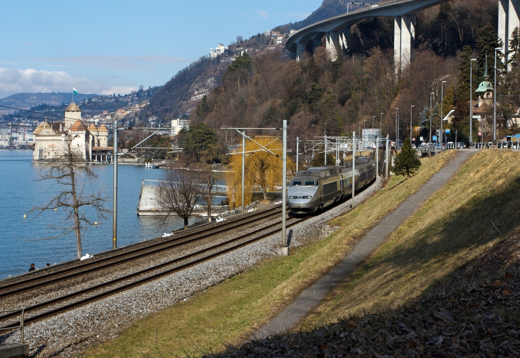 TGV Lyria (112) der Verbindung Paris–Dijon–Lausanne–Brig bediehnt, er f�hrt hier am 26.02.2012 bei  Clos du Moulin am Genfersee Richtung Brig entlang, hinten Ch�teau de Chillon, dahinter Montreux.