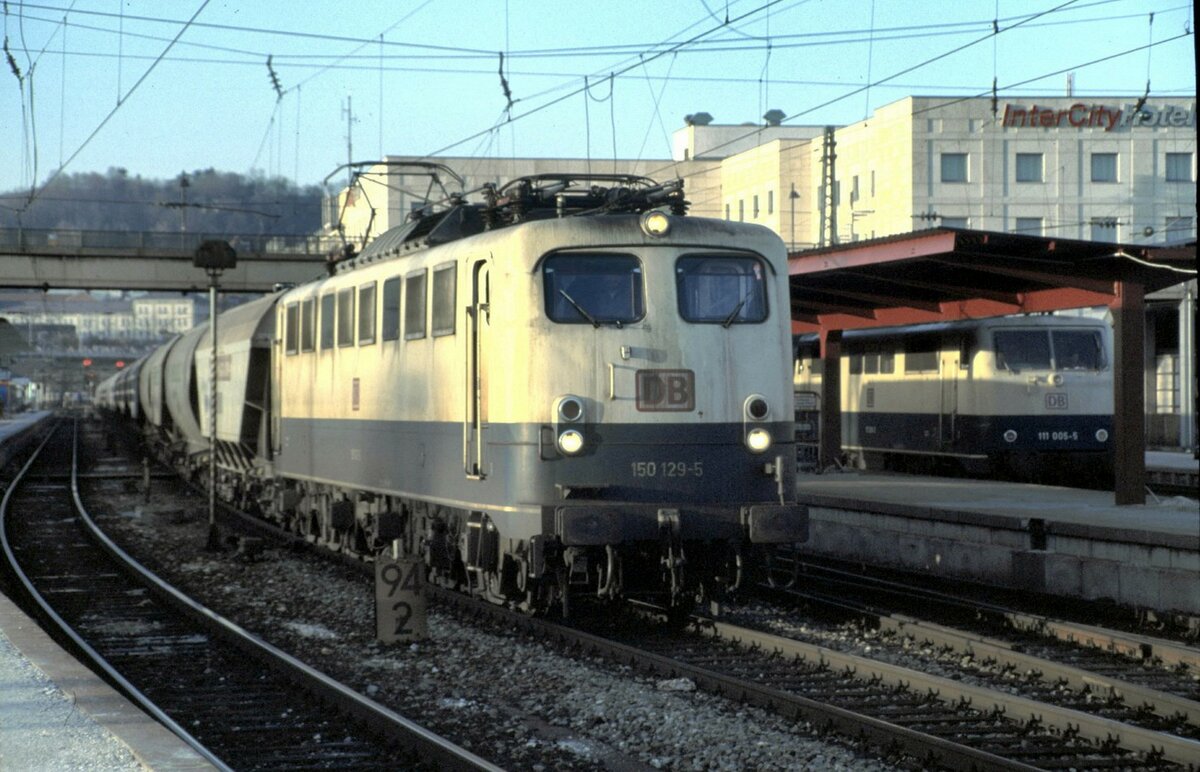 150 129-5 und auf den Bayerischen Gleisen (hier 21) 111 005-5 in Ulm am 13.03.1999. Der Güterzug hält auf dem Durchgangsgleis, um einen Lokführerwechsel stattfinden zu lassen.