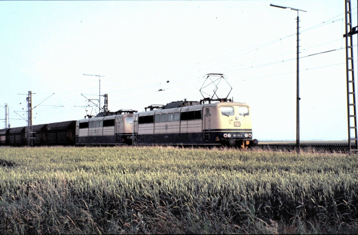 151 115-3 und eine weitere 151 mit Mittelpufferkupplung in Doppeltraktion vor einem leeren Erzzug bei Vechelde am 16.08.1981.