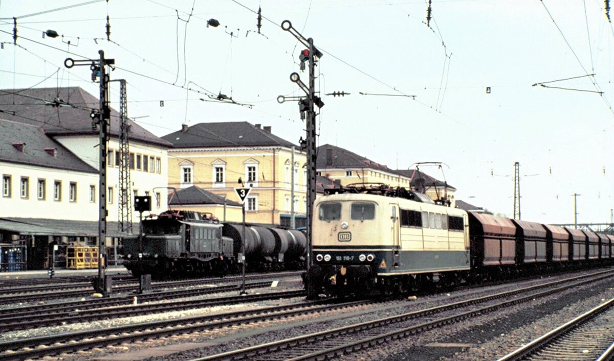 151 118-7 mit Mittelpufferkupplung und Schüttgutseitenentladewagen Ganzzug (6-achsig)und eine 194 mit Kesselwagenganzzug jn Regensburg am 25.04.1982.