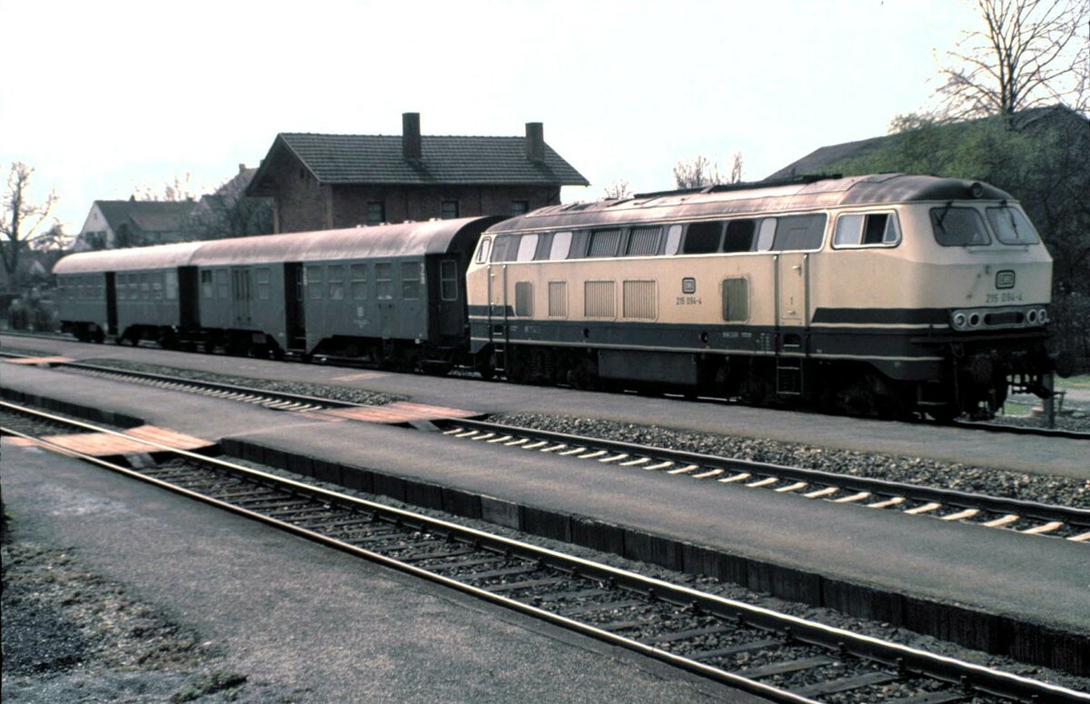 215 094-4 mit Umbauwagen mit Gepäckabteil und Schwanenhals-Drehgestellen und einem Umbauwagen der Allgäu-Zollern-Bahn in Illertissen (grüner Streifen) im Februar 1990.