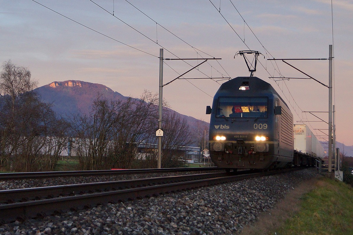 BLS: BLS Re 465 009-9 mit einem Containerzug bei Niederbipp im allerletzten Abendlicht bei Niederbipp. Rechts im Bilde ist die Klus bei Balsthal sichtbar.
Foto: Walter Ruetsch
