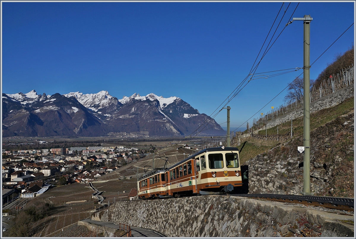 Der A-L BDeh 4/4 302 schiebt seine Bt 351 oberhalb von Aigle Richtung Leysin. Recht unten im Bild ist die Station Dépot A-L zu erkennen, wo die 230 Promille Rampe ihren Anfang nimmt. 17. Feb. 2019