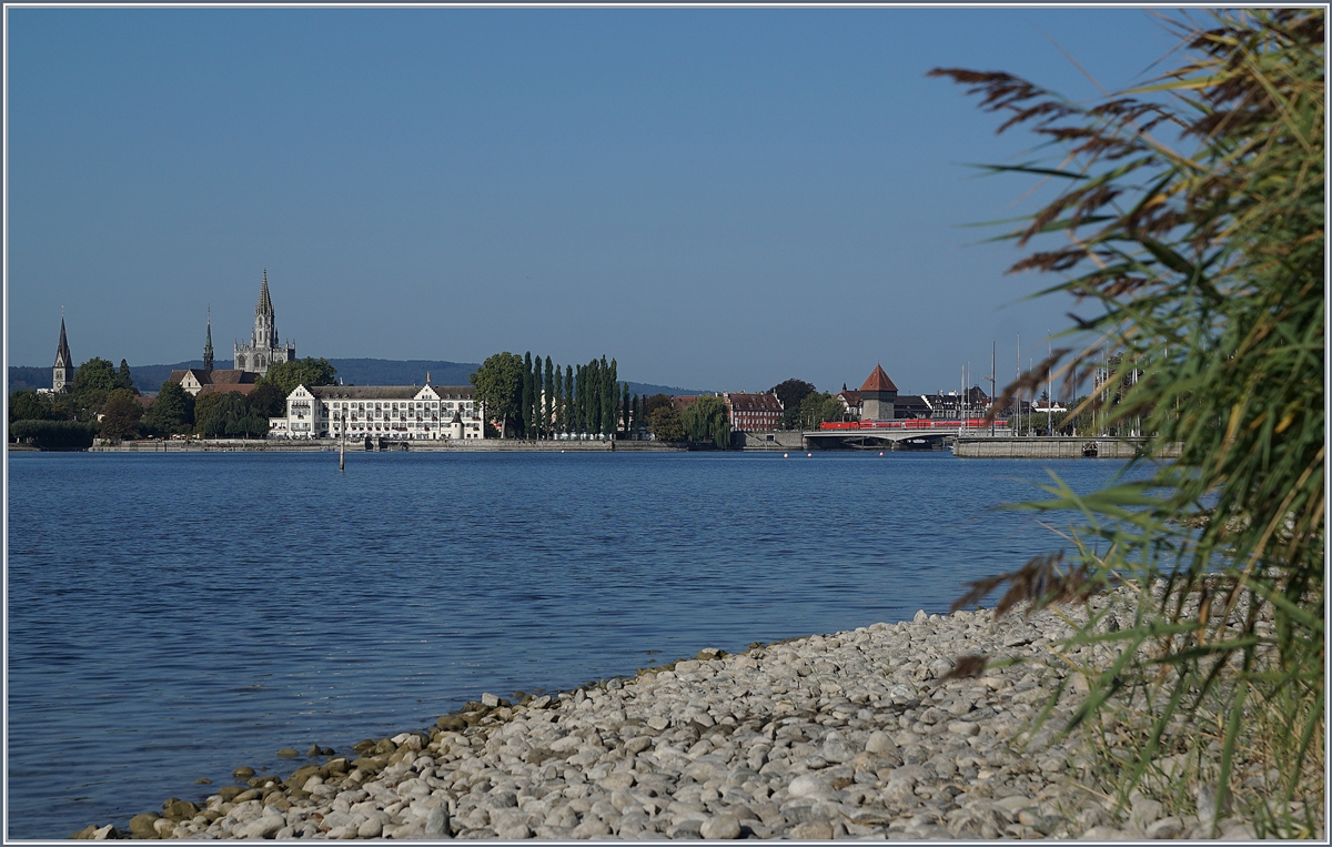 Der Rhein verbindet, der Rhein trennt; doch Brücken überwinden die Trennung. Nachdem der Alpenrhein bei Lustenau von der  neuen Eisenbahnbrücke über den Rhein ein letztes mal überbrückt wurde, fliesst er durch den Bodensee und wird just an jener Stelle, wo er wieder zum Rhein wird erneut überbrückt: Die  Alte Rheinbrücke  in Konstanz von 1860, die jedoch 1938 grundlegend umgebaut wurde. Bei einer Gesamtlänge von 127.8 Meter ist die Brücke mit 26.95 recht breit, wobei nach dem Verzicht auf den Ausbau auf Doppelspur der Bahnstrecke der dafür freigehalten Korridor 1957 genutzt werden konnte und somit heute neben fünf Fahrspuren für den Strassenverkehr der Bahn nur ein Gleis zur Verfügung steht, welches rege genutzt wird. Der Rhein, welcher hier den Bodensee verlässt und nun von Kilometer zu Kilometer gezählt wird, heisst hier Seerhein und somit wird die  alte Rheinbrücke  auch  Seerheinbrücke  genannt. Im Bild eine DB 146 mit einem  Schwarzwald  -RE.
19. Sept. 2018