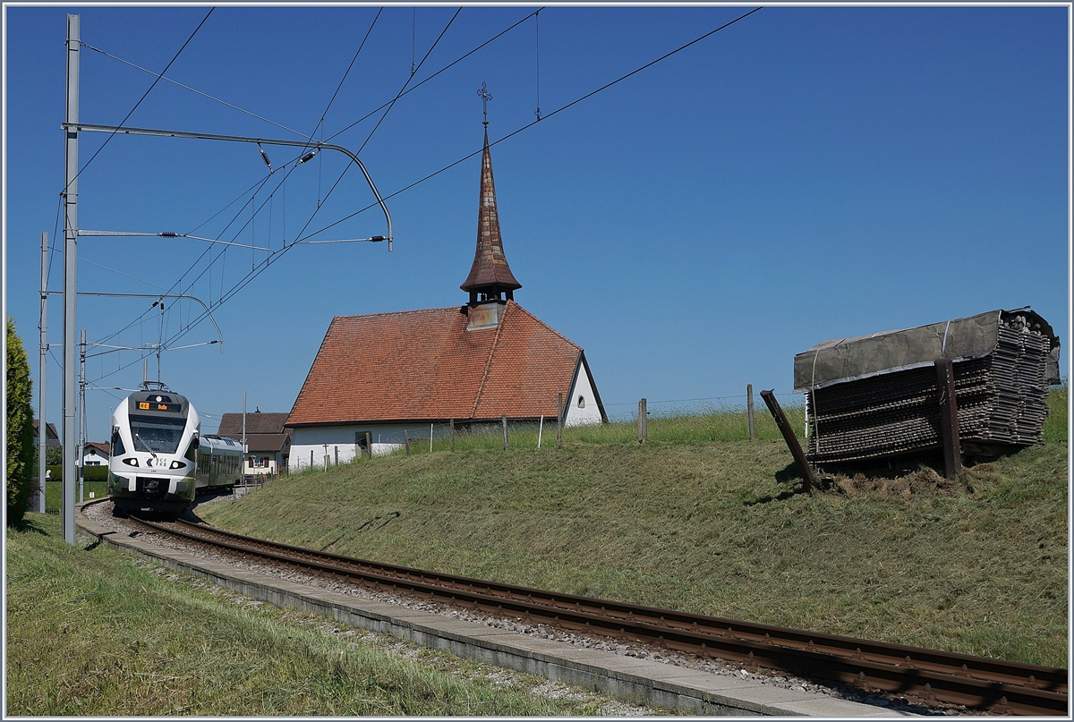 Der TPF RABe 527 198  BCF / FKB  (Kantonalbankwerbezug) erreicht Vaulruz, links im Bild die mittlerweile bekannte Kapelle von Vaulruz, rechts, die hier typischen an den Gleisböschung stehenden Bretterstapel.

19. Mai 2020 