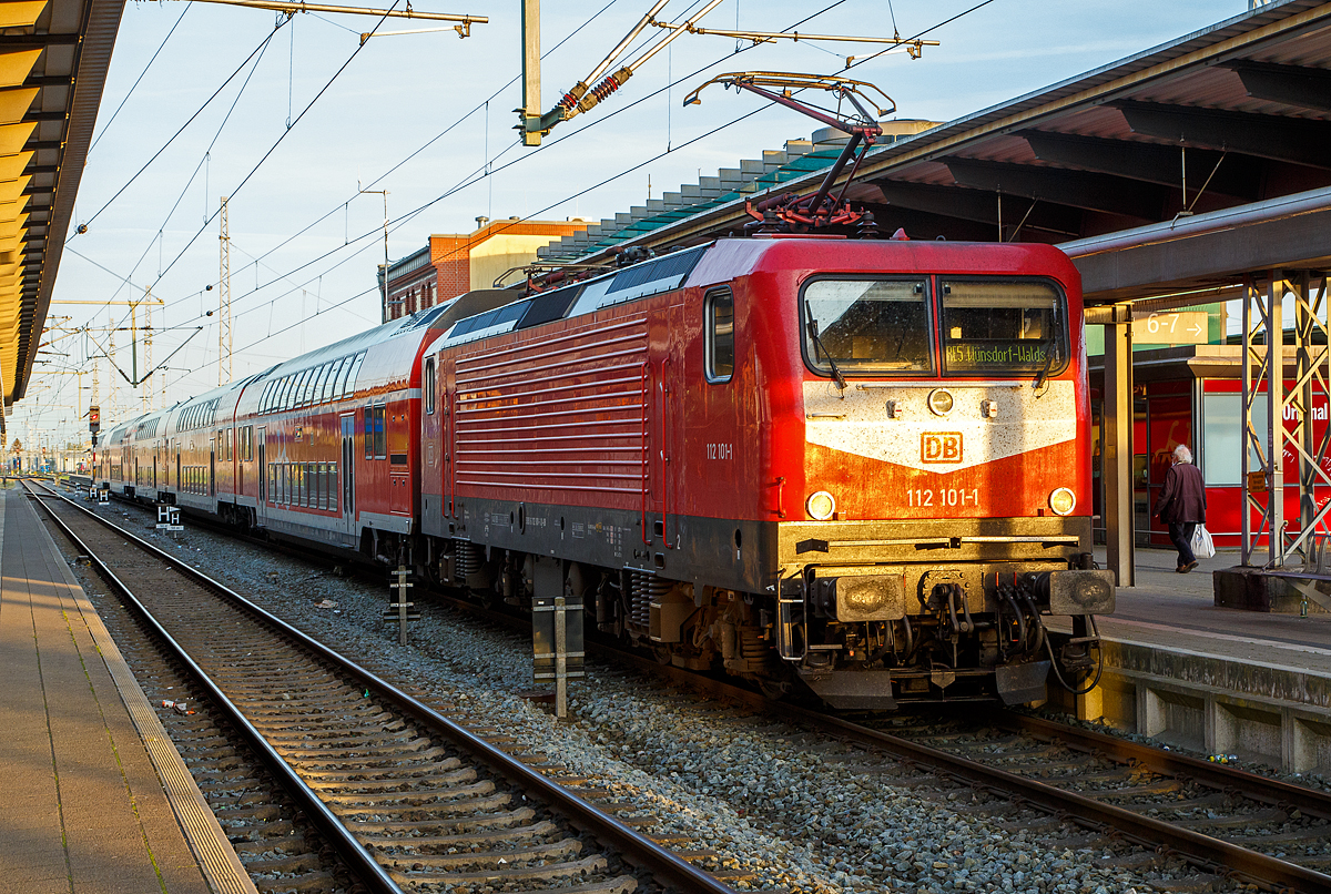 Die 112 101-1 (91 80 6112 101-1 D-DB) der DB Regio Nordost steht am 14.05.2022, mit dem RE 5 (Rostock – Stralsund – Berlin – Wünsdorf-Waldstadt), im Hbf Rostock zur Abfahrt bereit.

Die Lok wurde 1992 von AEG in Hennigsdorf unter der Fabriknummer 21477 gebaut und an die Deutsche Reichsbahn als DR 112 101-1 geliefert. Aus der Hennigsdorfer Lokschmiede LEW - VEB Lokomotivbau Elektrotechnische Werke „Hans Beimler“ Hennigsdorf wurde wieder von der AEG übernommen. DB und DR bestellten jeweils 45 Lokomotiven der Baureihe 112.1. Die an die DR gelieferten Maschinen bekamen die Betriebsnummern 112 101-1 – 112 145-8, die an die DB gelieferten die 112 146-6 – 112 190-4. Nach dem Zusammenschluss der beiden deutschen Bahnen zum 01.01.1994 zur DB AG wurden aus den DR Maschinen DB, so auch die 112 101-1.
