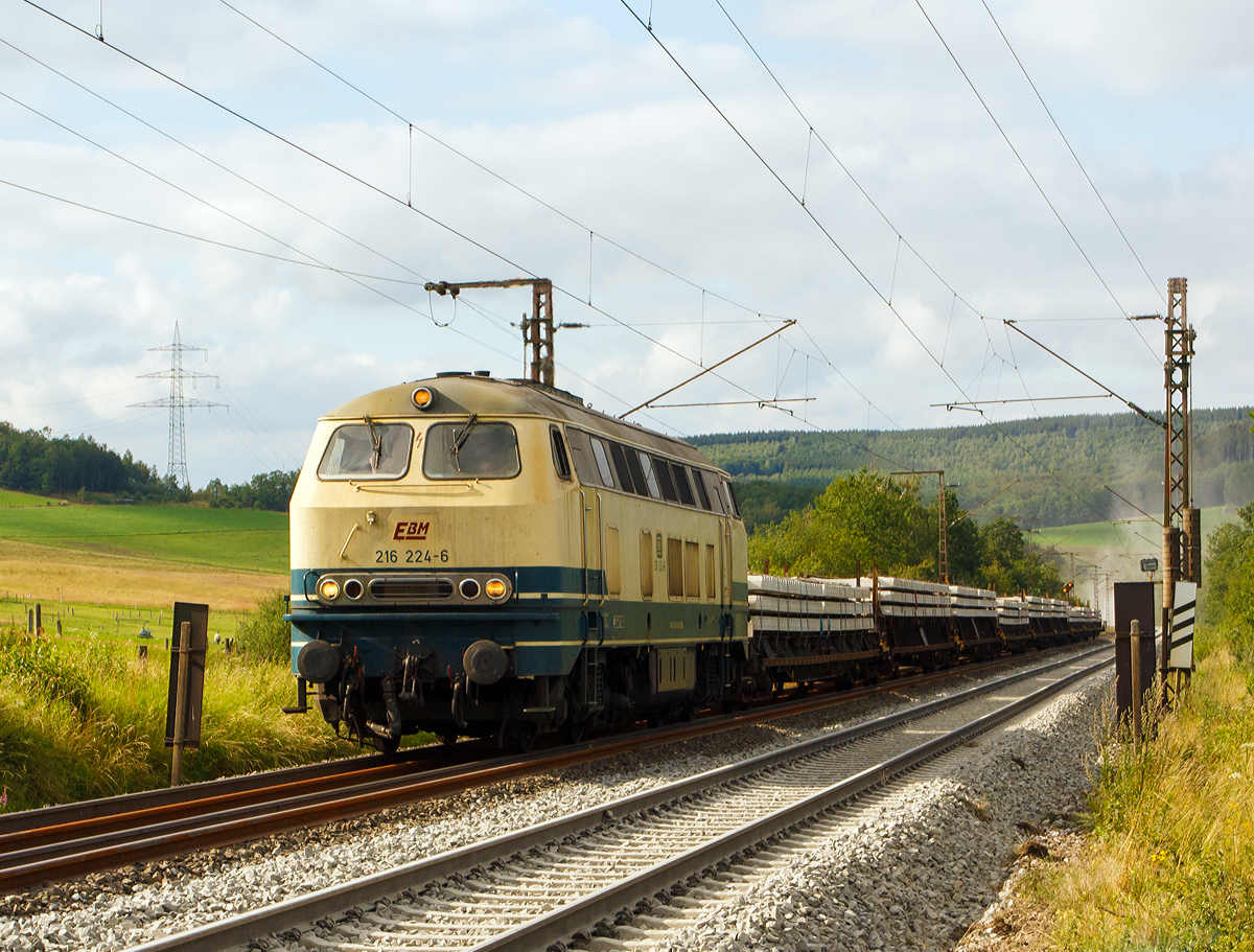 
Die 216 224-6 der EBM Cargo (Gummersbach) kommt mit einem Schwellenzug am 29.07.2011 von Siegen über das Baugleis in Wilnsdorf-Rudersdorf (KBS 445). Die Lok wurde 1968 bei Krupp unter der Fabriknummer 4885 gebaut.

Die Baureihe V 160 (ab 1968: Baureihe 216) war die erste Variante der V 160-Familie der Deutschen Bundesbahn, die im Nachkriegs-Neubauprogramm als einmotorige Großdiesellokomotive für den mittelschweren Streckendienst projektiert wurde.
Angetrieben wird die Lok vom Dieselmotor MTU 16 V 538 / 653 TB 10 mit 16 Zylindern und einer Leistung von 1900 PS bei 1500/min. Die Leistung gelangt über ein hydraulisches Getriebe mit zwei Wandlern und einer Kupplung und Gelenkwellen zu den Radsatzgetrieben in den beiden zweiachsigen Drehgestellen. 

Zusätzlich zum Fahrdieselmotor ist ein kleiner Hilfsdieselmotor vorhanden, welcher beim Aufrüsten -- insbesondere zum Betrieb des Dampfheizkessels -- und als Kompressor zur Luftversorgung genutzt werden kann. 