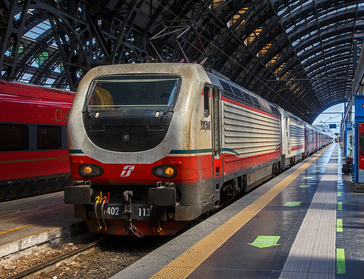 Die beiden E.402B 113 und 111 (91 83 2402 113-x I-TI und 91 83 2402 111-5 I-TI) erreichen am 12.07.2022, mit einem Trenitalia InterCity Notte (ICN), den Bahnhof Milano Centrale (Mailand Hbf).

Die FS E.402B ist eine Weiterentwicklung der E.402A, verfügt jedoch gegenüber ihrem Vorgängermodell zum Beispiel über ein höheres Gewicht sowie einen neu gestalteten und futuristischeren Wagenkasten. Die Höchstgeschwindigkeit ist jedoch mit 200 km/h etwas geringer als bei der E.402A (mit 220 km/h). Von den Loks wurden 80 Stück zwischen 1997 und 2000 von Ansaldo, Firema Trasporti (Fiore-Casertane), ITIN und SOFER gebaut.

Die Baureihe E.402B ist eine Mehrstromlokomotive, sie kann unter 3.000 V Gleichstromspannung, dem hauptsächlichen italienischen Bahnnetz, aber auch auf den italienischen Schnellfahrstrecken mit 25 kV, 50 Hz Wechselstrom fahren. Fernerhin kann sie unter 1.500 V Gleichstrom betrieben werden, dann hat sie aber nur die halbe Leistung. 

Die Lok ist eine vollelektronische Chopperlokomotive, das heißt, wenn die Lokomotiven unter 3.000 V DC fährt, wird der Strom mit Hilfe eines Zerhackers in Wechselstrom umändern, der dann schließlich die Motoren antreibt. 

TECHNISCHE DATEN:
Spurweite:  1435 mm (Normalspur)
Achsformel: Bo'Bo'
Länge: 19.420 mm
Drehzapfenabstand: 10.450 mm
Achsabstand im Drehgestell: 2.850 mm
Treibraddurchmesser:  1.250 mm
Dienstgewicht: 89 t
Höchstgeschwindigkeit: 200 km/h
Stundenleistung: 6.000 kW
Dauerleistung: 5.600 kW
Anfahrzugkraft: 280 kN
Stromsysteme: 3000 V DC, 25 kV - 50 Hz AC und 1500 V DC (bei halber Leistung)