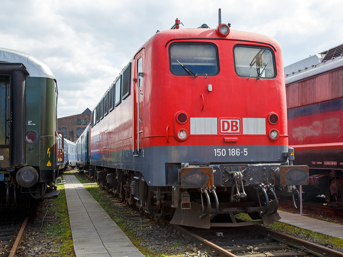 Die DB 150 186-5 am 09.04.2016 im DB Museum Koblenz. 

Die DB verschrottete fast alle ihre Loks der Baureihe 150 in den Jahren 2003/04. Erhalten geblieben sind nur zwei Maschinen als Museumsloks. Dies sind: Die 150 091 als E 50 091 im Ablieferungszustand und diese 150 186-5 im letzten Betriebszustand in verkehrsroter Lackierung, beide kann man im DB Museum Koblenz besichtigen. Damit sind jeweils eine 150er der ersten Bauserie und der letzten Bauserie erhalten geblieben. Die 150 186 ist zudem noch ein Unikat, da sie eine der mit Schweizpaket ausgerüsteten 150er ist; sie besitzt ein Schweizer Stromabnehmer-Schleifstück und den Schweizer Zugbahnfunk.  

Die 150 186-5 wurde 1972 von der Krauss-Maffei AG in München unter der Fabriknummer 19620 gebaut, der elektrische Teil ist von SSW (Siemens-Schuckert-Werke).
    
Die Baureihe E 50 (ab 1968 als Baureihe 150 geführt) ist eine für die Deutsche Bundesbahn erstmals im Jahre 1957 gebaute Einheitselektrolokomotive für den schweren Güterverkehr. Die letzten Exemplare wurden im Jahr 2003 von der Deutschen Bahn ausgemustert.

1950 beschloss der zuständige Fachausschuss der Bundesbahn die Beschaffung zweier Grundtypen von Elektro-Einheitslokomotiven mit weitgehend standardisierten Bauteilen. Dies sollten eine sechsachsige Güterzuglok auf Basis der Baureihe E 94 und eine an die Baureihe E 44 angelehnte Mehrzwecklokomotive sein. Die Führerstände sollten so gebaut werden, dass die Lokführer ihre Arbeit sitzend verrichten konnten. Bei allen vorherigen Baureihen mussten sie stehend fahren, um die Aufmerksamkeit zu erhöhen.

Die Mehrzwecklok erhielt zunächst den Arbeitstitel E 46, wurde jedoch in Baureihe E 10 umbenannt, nachdem sie durch Erhöhung der geforderten Höchstgeschwindigkeit formell eine Schnellzuglokomotive wurde. Die schwere Güterzuglok erhielt die Bezeichnung Baureihe E 50. Die Entwicklung, die zu weitgehend einheitlichen Baugruppen führte, begann 1952 mit der Lieferung von fünf Versuchslokomotiven der Baureihe E 10.0, in denen die Anforderungen des Bundesbahn-Zentralamts und die Vorstellungen der Hersteller verwirklicht waren.

Die ab 1957 gebaute E 50 (ab 1968 BR 150) war die erste schwere Güterzug-Ellok des Einheitslokomotivprogramms. Bis 1973 wurden in mehreren Serien insgesamt 194 Lokomotiven geliefert, die zunächst die gleichen Aufgaben wie die schweren Lokomotiven der Baureihe E 94 vor dem Zweiten Weltkrieg übernahmen und diese später ersetzten.

Die Baureihe 150 fand ihren Nachfolger in der Baureihe 151, weil ihre Leistungsfähigkeit für das 1969 beschlossene neue betriebliche Leitprogramm für den schweren Güterzugdienst nicht mehr ausreichte. Zudem war seitens des Betriebsdiensts an der Baureihe 150 seit jeher kritisiert worden, dass ihre Zugkraft oberhalb von 80 km/h stark einbrach. Einsätze mit Geschwindigkeiten über 80 km/h bei höheren Zugkräften führten häufig zu Fahrmotorschäden. Mit Erscheinen der modernen Drehstromlokomotiven der Baureihe 152 wurde die Baureihe 150 verstärkt ausgemustert. Das letzte Bahnbetriebswerk für den Einsatz war Kornwestheim, von wo aus sie neben dem schweren Güterzugdienst auch im Schiebedienst auf der Geislinger Steige und der Spessartrampe eingesetzt wurden. Zum Jahresende 2003 schieden die Lokomotiven der Baureihe 150 vollständig aus dem Dienst bei der DB aus.

Wie alle Lokomotiven des Einheitslokomotivprogramms hatte die E 50 Drehgestelle als geschweißte Kasten-Konstruktionen mit Drehzapfen und geschweißte Kastenaufbauten mit Lüftergittern. Der Rahmen stützte sich über Schraubenfedern und Gummielemente auf die Drehgestelle ab. Die beiden Drehgestelle waren mit einer Querkupplung miteinander verbunden, um ein Anheben des vorderen Drehgestelles beim Anfahren schwerer Züge zu vermeiden. Als Bremse wurde eine indirekt wirkende Druckluftbremse Bauart Knorr und zum Rangieren eine direkt wirkende Zusatzbremse verwendet.

Auf dem Dach befanden sich die Scheren-Stromabnehmer Bauart DBS 54a. Die Fahrmotoren der Baureihe 150 tragen die Bezeichnung EKB 760 und sind kleiner, leichter und schwächer als die SSW-Motoren WBM372-22 der Baureihen 110 / 140. Gegenüber deren Nennleistung von 925 kW weisen sie nur eine solche von 735 kW auf. Sie sind zwölfpolig und stammen technisch von den in der E 94 verwendeten AEG-Motoren ab. Sechs Radiallüfter für jeden Fahrmotor sorgen für die Kühlung. Die erste Serie der E 50 (001-025) erhielt noch den bewährten Tatzlager-Antrieb, da man dem Gummiringfeder-Antrieb der Siemens-Schuckert-Werke (SSW) nicht zutraute, große Leistungen ohne übermäßigen Verschleiß auf die Schienen zu bringen. Nachdem sich diese Bedenken als unbegründet erwiesen hatten, erhielten auch die nachfolgenden E 50 den Gummiringfeder-Antrieb.

TECHNISCHE DATEN der BR 150:
Gebaute Anzahl: 194
Spurweite: 1.435 mm (Normalspur)
Achsformel: Co'Co'
Länge über Puffer: 19.490 m
Drehzapfenabstand: 9.700 mm
Drehgestellachsstand: 4.360 mm
Höhe: 3.954 mm
Breite: 3.130 mm

Treibraddurchmesser: 1.250 mm
Höchstgeschwindigkeit: 100 km/h
Leistung: 4.500 kW bei 79 km/h
Anfahrzugkraft: 441 kN
Dienstgewicht: 128,0 t
Radsatzfahrmasse: 21,0 t
Anzahl der Fahrmotoren: 6
Antrieb: Gummiringfeder (anfangs Tatzlager)
Stromsysteme: 15 kV 16 2/3 Hz, Oberleitung

