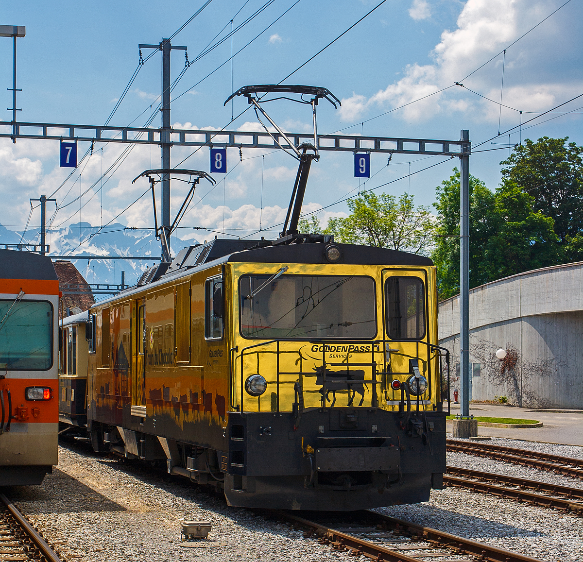 Die goldene  Schokoladenlok  bzw.  Train du Chocolat , die MOB GDe 4/4 6003 „Saanen“ steht am 28.05.2012 mit einem MOB Panoramic Express im Bahnhof Bulle (Kanton Freiburg).

Die Loks mit Gep�ckabteil wurden 1983 von der Schweizerische Lokomotiv- und Maschinenfabrik (SLM) in Winterthur gebaut, die elektrische Ausr�stung ist von BBC.

Korrekt h�tten diese starken Maschinen eigentlich „De 4/4“ hei�en m�ssen, aber die MOB und auch der Hersteller SLM haben diese Gep�cktriebwagen, die sie nach strenger Definition sind, immer als „Lokomotiven mit Gep�ckabteil“ bezeichnet, daher „GDe“. Verdient haben sie das sicher, bis zur Einf�hrung der Ge 4/4 gut zehn Jahre sp�ter waren sie die schnellsten meterspurigen Triebfahrzeuge Europas. 

Das seit 1976 steigende Verkehrsaufkommen f�hrte zur �berlegung, neue, leistungsstarke Triebfahrzeuge anzuschaffen. Sechsachsige Lokomotiven kamen aus Kostengr�nden nicht in Frage, man entschied sich daher f�r vierachsige Fahrzeuge. Die Vorgabe war, dass sie in der Lage sein mussten, einen Zug von 110 t (entsprechend f�nf Panoramawagen) auf den steilsten Streckenabschnitten mit ca. 40 km/h zu ziehen. Im Herbst 1981 wurden dann, mit finanzieller Unterst�tzung des Bundes sowie der Kantone Waadt, Fribourg und Bern vier Lokomotiven bestellt. Bei der Konstruktion standen Fahrzeuge der Furka-Oberalp-Bahn Pate: die Drehgestelle entsprechen weitgehend jenen der FO Tunnelloks Ge 4/4 III. Der Kasten entstand in Anlehnung an die Gep�cktriebwagen Deh 4/4 II der FO. Als Besonderheit weisen die GDe 4/4 6001-6004 einen kleines Gep�ckabteil und eine Durchgangsm�glichkeit auf den Frontseiten auf. Als echte Universalloks mussten sie schwere Personenz�ge ebenso ziehen wie den Rollbock-Verkehr mit normalspurigen G�terwagen bew�ltigen k�nnen.

Bei den fremderregten Fahrmotoren handelt es sich um unkompensierte Wellenstrommaschinen, die von einem Thyristorumrichter gespeist werden. Durch den Einsatz r�ckw�rtsleitender Thyristoren gelang es, die Anzahl der Halbleiterelemente m�glichst klein zu halten. Der Fahrtrichtungswechsel und die Umschaltung zwischen Fahr- und Bremsbetrieb erfolgt mittels elektropneumatischer Sch�tze.
Anfang 1982 schloss sich auch die benachbarte GFM dieser Bestellung mit zwei baugleichen Fahrzeugen an, es waren die GMF 101 („Ville de Bulle“) und GMF 102 („Neirivue“), sie waren daf�r eingerichtet, freiz�gig auch auf dem MOB-Netz verkehren zu k�nnen. Die MOB erwarb 2008 die beiden GFM-Maschinen, so dass heute alle sechs der MOB geh�ren.

Ab Mitte 1983 erfolgte die Auslieferung der Fahrzeuge an die Bahngesellschaften. Die MOB Maschinen bekamen die neue Serienbezeichnung „6000“ (Nr. 6001 bis 6004) und individuelle Namen und Wappen. Die neuen Maschinen erf�llten alle Erwartungen, bei Testfahrten konnten sie auf den steilsten Streckenabschnitten sogar sechs statt der geforderten f�nf Panoramawagen ziehen. Sie stellten neue europ�ische Geschwindigkeitsrekorde f�r meterspurige Triebfahrzeuge auf, im Simmental erreichte die 6001 am 20. 7. 1983 eine Geschwindigkeit von 105 km/h, die 6003 am 3. 11. 1983 sogar 110 km/h. Heute sind zwei GDe der MOB speziell f�r den Einsatz im Crystal Panoramic Express Dienst hergerichtet. Bei diesen modernen Luxusz�gen ist die Lok in der Zugmitte eingereiht. Der Lokf�hrer sitzt in einer Dachkanzel im Steuerwagen (Ast) �ber den Passagieren, die den Blick nach vorne auf die Strecke genie�en k�nnen.

TECHNISCHE DATEN:
Bezeichnung: GDe 4/4
Betriebsnummern: 6001 – 6006 (davon zwei ex GMF 101 – 102
Anzahl Fahrzeuge: 6
Hersteller:	 SLM / BBC
Baujahr:1983
Spurweite: 1.000 mm (Meterspur)
Achsanordnung:	Bo'Bo'
L�nge �ber Puffer: 16.400 mm
Drehzapfenabstand: 9.000 mm
Achsabstand im Drehgestell: 2.600 mm
Treibraddurchmesser: 1.070 mm (neu)
H�chstgeschwindigkeit:100 km/h betrieblich (m�glich 110 km/h)
Dienstgewicht:48,2 t
Max Zuladung: 1,5 t
Ladefl�che: 8,70  m�
Fahrleitungsspannung: 900 V, DC (600 .. 1050 V)
Anzahl Fahrmotoren:	4 (Typ 4 FRO 3238)
Stundenleistung am Rad:1.068 kW
Dauerleistung am Rad:1.016 kW
Anfahrzugkraft am Rad:172 kN
Stundenzugkraft am Rad: 86,5 k (bei 43,4 km/h)
Dauerzugkraft am Rad: 80,7 kN (bei 44,2 km/h)
Bremskraft: 140 kN
Anh�ngelast bei 40 km/h: bei 30‰ 300 t / bei 70‰ 	110 t
Getriebe�bersetzung:	1 : 6
Bremsen: F / D / mDV Zug / C / Cr / X
