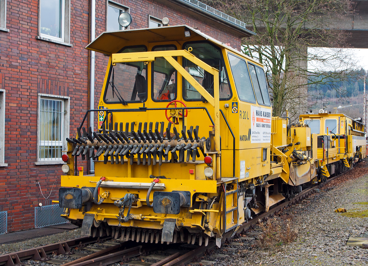 
Die Matisa Schotterplaniermaschine vom Tpy R 20 L (Schweres Nebenfahrzeug Nr. 97 16 38 501 17 – 3) und die Plasser & Theurer Zweischwellenstopfmaschine 09 - 32  CSM (Schweres Nebenfahrzeug Nr. 97 40 68  524 17 -9) beide von der Firma Hans Kaiser GmbH & Co. KG (Tann) abgestellt am 25.12.2014 am KSW Bahnhof Siegen-Eintracht (Betriebsbereich Eisern-Siegener Eisenbahn).

Die Schotterplaniermaschine wurde 1993 von MATISA Mat�riel Industriel S.A in Crissier (Schweiz) unter der Fabriknummer 6714 gebaut und an die Th�ringer Gleisbau geliefert.

Die modulare Baureihe R 20 wird bereits seit 1987 hergestellt, wir hier ist es Normalspur-Maschine. Entwickelt wurden diese Maschinen jedoch speziell f�r Schmalspurnetze oder Netze mit begrenzter Achslast entwickelt. Der Schotterpflug der Baureihe R 20 kann in beide Fahrtrichtungen (Richtungsunabh�ngig) arbeiten, dies hat den Vorteil Leerfahrten der Maschine zu vermeiden und Schotterverschiebungen von einer Bettungsschulter zur anderen in einem einzigen Arbeitsdurchgang durchzuf�hren. Daraus ergibt sich ein bemerkenswerter Zeitgewinn, wobei meist das Stopfen den gr��ten Zeitaufwand ben�tigt. Die gro�e Beweglichkeit der Seitenpfl�ge erm�glicht auch bei hohen Geschwindigkeiten das Umgehen von Hindernissen. Die Anpassung an alle Gleisschulterprofile und das Arbeiten im Seitenbereich der Gleise erfolgt ohne Verletzung des Lichtraumprofils des Nachbargleises.

Die vor der Kabine angeordneten Zentralpfl�ge bleiben stets im Sichtbereich des Bedieners. Alle Maschinen sind mit einem doppelten Bedienungspult ausger�stet. Die reichlich dimensionierte Kabine bietet eine ausgezeichnete Sicht auf den Arbeitsbereich und das Gleis.

Die B�rsteneinheit ist mit einem Aufnahmekasten ausger�stet, der den wegschleudernden Schotter aufnimmt und auf ein F�rderband leitet, das ihn entweder seitlich auf die Gleisschultern wirft (Version L) oder in einen Silo bef�rdert (Version LS und LT).

Technische Daten der Schotterplaniermaschine R 20 L:
Spurweite: 1.435 mm (lieferbar 1.000 bis 1.676 mm)
Achsanzahl: 2
Achsabstand: 6.200 mm
L�nge �ber Puffer: 13.690 mm
Eigengewicht: 28,5 t
Anh�ngelast: 20 t
Zur Mitfahrt zugel. Personen: 2
H�chstgeschwindigkeit: 90 km/h
Max. Geschwindigkeit beim Planieren: 12 km/h
Max. Geschwindigkeit beim Kehren: 3 km/h
Kleinster befahrbarer Kurvenradius: R 75 m
Motor: DEUTZ-Dieselmotor vom Typ F 10 L 413 F
Motorleistung: 196 kW / 2300 U/min