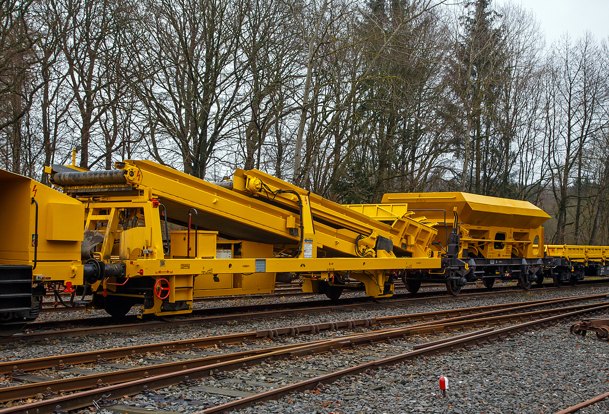 Die Plasser & Theurer Beladestation BLS 2000 (BLS 40 – 2000) der HERING Bahnbau (Burbach) Schweres Nebenfahrzeug Nr. D-HGUI 99 80 9552 123-8, ex 97 19 26 502 57-8 ist am 20.12.2020 auf dem Betriebshof der Westerwaldbahn (WEBA) auf der Bindweide bei Steinebach/Sieg abgestellt.

Die Beladestation wurde 1993 von Plasser & Theurer unter der Fabriknummer 2161 gebaut.

Die BLS 2000 ist ein zweiachsiges, gleisfahrbares Gerät. Die BLS 2000 kann unter spannungsführenden Fahrleitungen eingesetzt werden. Sie kann mit MFS 38, 40, 100, BSW 2000 und 6000 gekoppelt werden. Der Boden des Aufnahmebandes und des Übergabebandes ist als steuerbares Band mit einer Förderbreite von 1.920 mm ausgebildet. An der Baustelle angekommen, ist eine Aufrüstzeit von ca. 3 Minuten nötig. Der Aufnahmetrichter wird auf eine Höhe von max. 1,15 m über SOK abgesenkt und das Übergabeband wird ausgefahren. Hiernach können die Schüttgüter (alter Gleisschotter, Planum etc.) mittels Laderaupe, Radlader oder Bagger über die BLS in die MFS oder BSW verladen werden. Die Förderbänder werden hydraulisch angetrieben. Der Antrieb des Hydraulikaggregates erfolgt durch einen luftgekühlten Deutz Dieselmotor vom Typ F5L912 mit einer Leistung von 64 kW.

TECHNISCHE DATEN:
Achsanzahl: 2
Eigengewicht: 22.600 kg
Länge über Puffer: 12.900 mm
Achsabstand: 8.000 mm
Laufraddurchmesser: 730 mm (neu)
Höchstgeschwindigkeit: 100 km
Kleinster befahrbarer Gleisbogen: R 120 m
Bremse: KE-GP
Handbremse: Ja