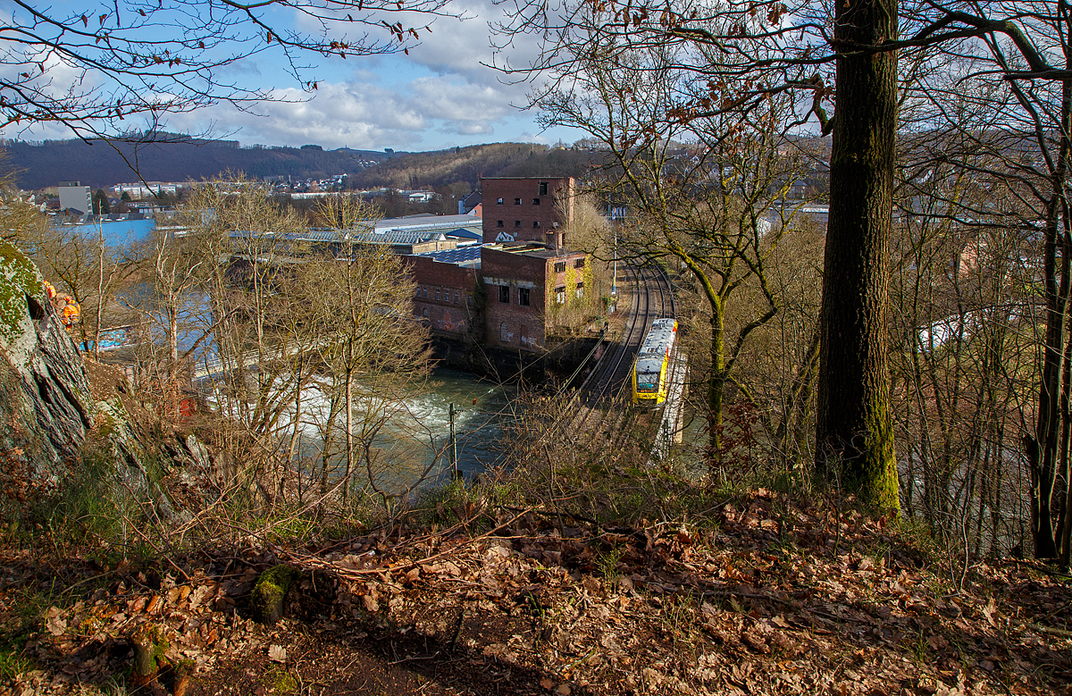 Ein LINT 48 der HLB (Hessische Landesbahn) hat am 26.02.2022 den 32 m kurzen Mühlburg-Tunnel durchfahren, überquert nun die Sieg und erreicht bald den Bahnhof Scheuerfeld (Sieg). Er fährt als RB 90  Westerwald-Sieg-Bahn  die Verbindung Westerburg - Altenkirchen - Au/Sieg - Betzdorf – Siegen.

Heute war die Siegstrecke zwischen Scheuerfeld (Sieg) und Niederhövels nur eingleisig befahrbar. Den Grund sieht man link im Bild, zwei Kletterer sind in der Felswand und führen eine Felsberäumung durch. Dabei werden alle losen Steine entfernt, um die Gefahr eines möglichen Steinschlages zu mindern.

Unten beim Wehr RWE Scheuerfeld einem Laufwasserkraftwerk, sieht am die Sieg toben. Dahinter die ehemalige Papierfabrik.
