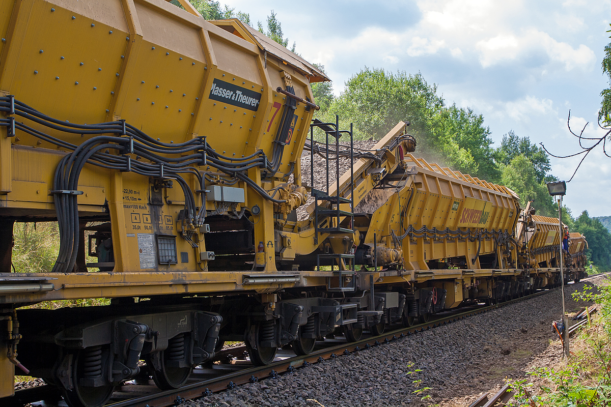Im Einsatz auf der Hellertalbahn (KBS 462) bei Würgendorf am 15.07.2013: Die Plasser & Theurer Hochleistungs-Bettungsreinigungsmaschine RM 95-800 W, Schweres Nebenfahrzeug Nr. 99 80 9414 001-4 D-MWGB, der MGW Gleis- und Weichenbau-Gesellschaft mbH & Co. KG (Berlin). 

Detailbild Abraum:
Die Maschine schiebt vier Materialförder- und Siloeinheiten MFS 100 der Schweerbau, in diese wird der Abraum (Altschotter) befördert. Weitere nun geleerte MFS 100 werden von einer Lok wieder heran geschoben und gleich wieder angekuppelt. Wenn diese angekuppelt sind, werden die vier, vor der Maschine befindlichen, gefüllten MFS 100 in diese wieder entleert.