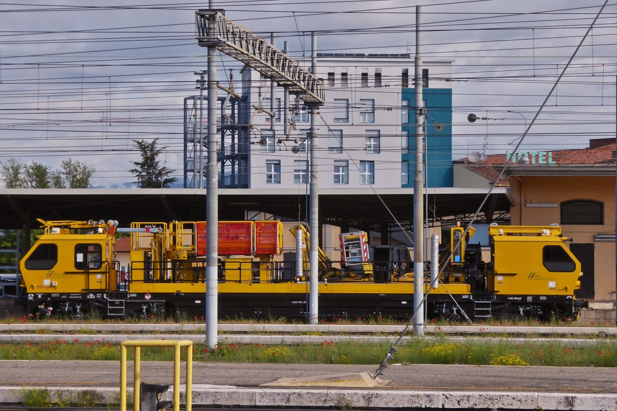 Mehrzweckfahrzeug OCPD 001, von Tesmec Rail, zur Wartung und Installieren von Oberleitungen mit Hilfe der an Bord installierten Spezialwerkzeuge, aufgenommen mit starkem Zoom, im Bahnhof von Verona Porta Nuova. Seitenansicht �ber mehrere Gleise Hinweg. 09.05.2025