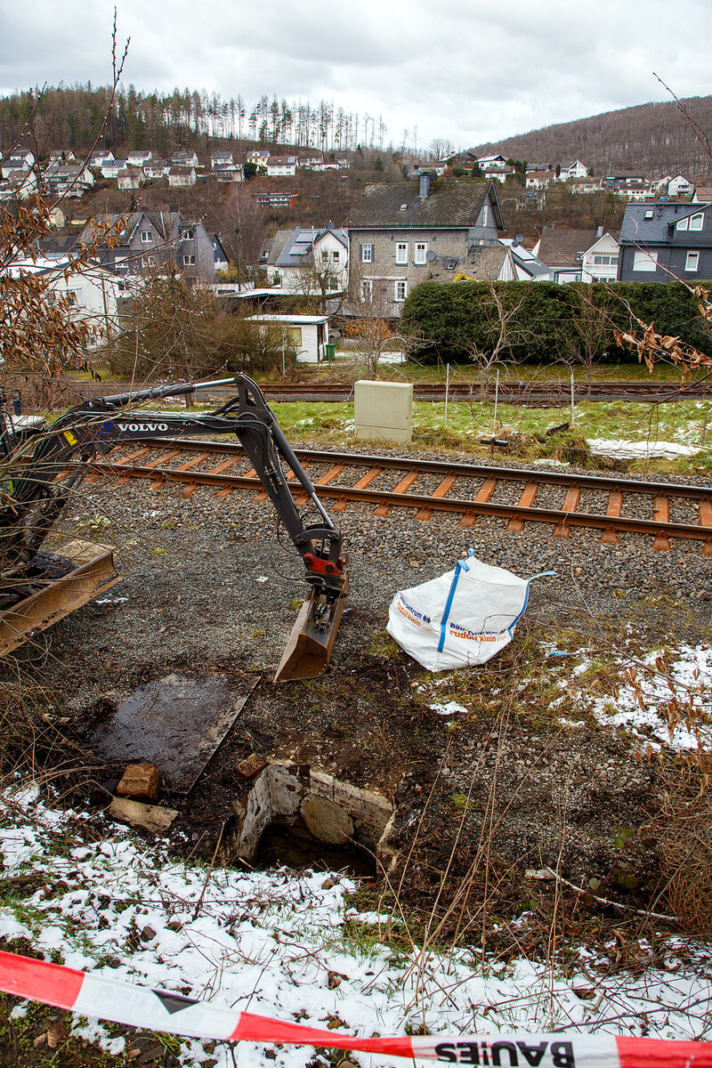 Schlimmer geht immer.....
Totalsperrung der Hellertalbahn (KBS 462 / Strecke 2651)
Nun ist Herdorf Bahntechnisch zur Insel geworden. 
Es gibt seit dem 10.03.23 eine Gleisuntersp�lung auf der Strecke 2651 bei km 91,0, so ist vorerst auch kein G�terverkehr von Haiger nach Herdorf m�glich. Da die Strecke Betzdorf – Herdorf, bereits wegen dem Felsstutz  am 23.12.2022, seitdem gesperrt ist Herdorf nun Bahntechnisch ganz abgeschnitten. 

Als ich heute Mittag (11:03.2023) unten an der Strecke bei km 91,0 war, wurde bereits durch eine Firma an der Entw�sserung gearbeitet. Der Sammler vor dem Funkmast (von Herdorf gesehen) war bereits offen und frei. Hier war aber auch oberirdisch kein Wasser zusehen, da dies nicht am Fundament vom Funkmast vorbei kam, und sich so den Weg durchs Gleisbett auf die andere Seite gesucht hatte. Bei dem Bild sieht man auch auf der anderen Seite vom Gleis Sands�cke um das Wasser von der Freien Grunder Eisenbahn fernzuhalten, die ja darunter liegt.