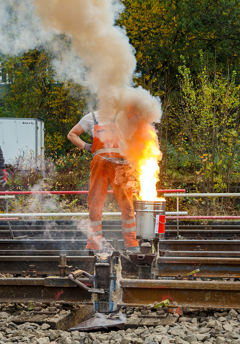 
Thermitschweißen am 31.10.2020 an der Hellertalbahn (KBS 462 / DB-Streckennummer 2651) hier Gleis 1 vom Bahnhof Herdorf.

Das Thermit-Schweißverfahren:
Das lückenlos verschweißte Gleis ist der Schlüssel zu effizienter schienengebundener Mobilität und der Garant für nachhaltigen, sicheren und komfortablen Schienenverkehr. 1895 ist es Hans Goldschmidt gelungen, die Reduktion von Metalloxiden mit Aluminiumpulver technisch verwendbar zu machen. Eine technische Revolution, die kurz darauf als Schweißtechnologie Eingang in die Bahnindustrie fand und damit Grundlage ist für eine sichere, komfortable und effiziente schienengebundene Mobilität. Die Deutsche Reichsbahn führte bereit 1928 das Thermit-Schweißen als Regelschweißverfahren ein. Bald folgten fast alle Eisenbahngesellschaften der Welt.
Denn damals wie heute gilt: Auf keinem Verkehrsweg werden Menschen und Güter zuverlässiger, komfortabler, wirtschaftlicher und ökologischer bewegt als auf der Schiene.

Fe²0³ + 2 Al ergibt 2 Fe + Al³0³ + Wärme 

Thermit ist ein Gemisch aus Aluminium-Granulat und Metalloxid, das nach einer Initialzündung stark exotherm reagiert.  Ein wesentlicher Bestandteil des Schweißprozesses ist die aluminothermische Reaktion. Hierfür wird die THERMIT-Schweißportion mit einem Anzünder entzündet. Es folgt eine chemische Reaktion, bei der Eisenoxid zusammen mit Aluminium unter starker Freisetzung von Reaktionswärme (ca. 3.000 °C) zu Eisen und Aluminiumoxid reagiert. Bei dieser Reaktion entsteht flüssiger Stahl, welcher genutzt wird, um Schienenenden miteinander zu verbinden. Diese enorme Hitzeentwicklung bewirkt eine schnelle, selbstständige Ausbreitung der Reaktion über das gesamte Gemisch. 
Eigentlich entsteht flüssiges, reines Eisen. Für die Schienenverbindung wäre dieses Thermit-Eisen jedoch noch zu weich. Daher werden den Thermit-Portionen stahlbildende Legierungszusätze zu gegeben und so stellen sich die richtigen Eigenschaften ein.

Die PROZESSSCHRITTE DER THERMIT®-SCHWEISSUNG 
1. Lücke herstellen: 
Zwischen den beiden zu verschweißenden Schienenenden wird die Lücke eingestellt.
2. Ausrichtung: 
Die Schienenenden werden so ausgerichtet, dass nach Bearbeitung der Schweißung die geometrischen Toleranzen eingehalten werden können.
3. Gießform montieren: 
An der Schweißlücke werden Gießformen angesetzt und abgedichtet.
4. Vorwärmen: 
Die Gießformen und das Abdichtmedium werden mittels Vorwärmbrenner getrocknet, die Schienenenden werden gleichzeitig vorgewärmt.
5. Thermit-Reaktion: 
Die Thermit-Reaktion wird im Reaktionstiegel gestartet.
6. Einguss: 
Der flüssige Thermit-­Stahl läuft in die Gießformen. Beide Schienenenden werden durch den zwischengegossenen Thermit-­Stahl angeschmolzen und miteinander verschweißt.
7. Abarbeitung: 
Nachdem der Thermit-Stahl erstarrt ist, werden Schweißgutüberstände abgearbeitet, meist mittels Hydraulischem Abschergerät.
8. Feinschliff: 
Nach der Abkühlung der Thermit-­Schweißung erfolgt der Feinschliff.
