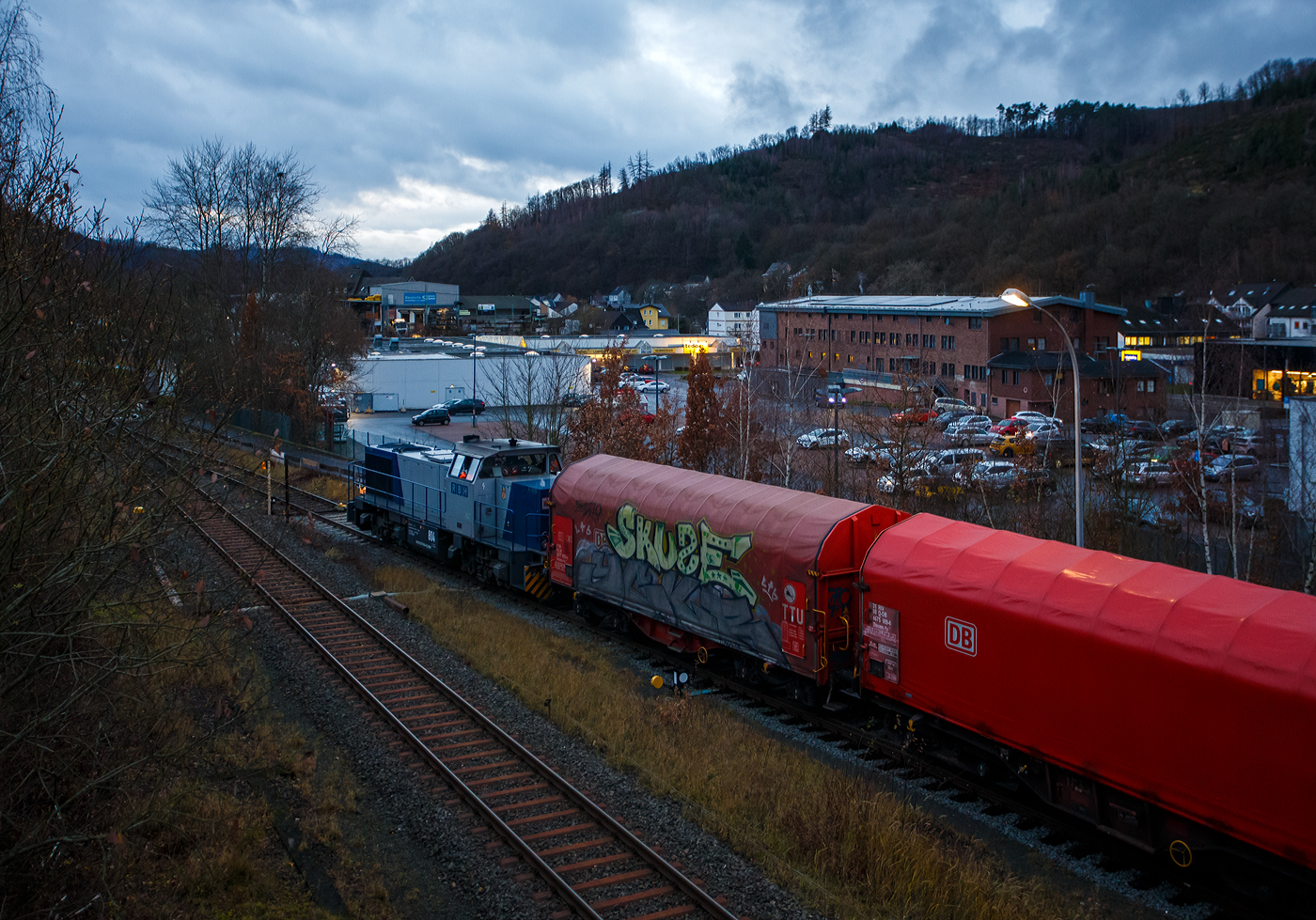 Aktuell besteht bei der KSW (Kreisbahn Siegen-Wittgenstein) immer noch Lokmangel, so ist zurzeit auch die RBH 804 / 275 804-9 (98 80 0275 804-9 D-RBH) eine MaK G 1206 der RBH - RAG Bahn und Hafen GmbH (Gladbeck), an die KSW vermietet. Hier steht sie am 08 Dezember 2025 um 16:23 Uhr, beim allerletzten Licht des Tages, mit einem Übergabegüterzug (leere Wagen) auf dem Rbf der KSW in Herdorf (Betriebsstätte Freien Grunder Eisenbahn - NE 447) vor der Gleisspeere zur Hellertalbahn. Die Helligkeit des Bildes täuscht etwas über die eigentlichen tatsächlichen Lichtverhältnisse hinweg.