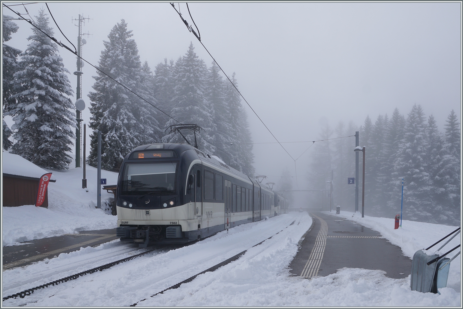 Auf der CEV Gipfelstation Les Pléiades wartet der CEV MVR ABeh 2/6 7502 auf die Abfahrt nach Vevey. Im Hintergrund ist ein weiterer ABeh 2/6 zu sehen, der später als Schülerzug nach Blonay verkehren wird. 

29.Jan. 2026