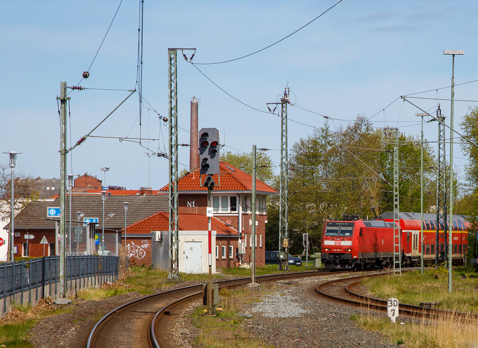 Blick vom Bahnhof auf das Stellwerk Norden Fahrdienstleiter (Nf) am 01.05.2022, während rechts die 146 102-9 mit dem RE 1 nach Hannover den Bahnhof erreicht.