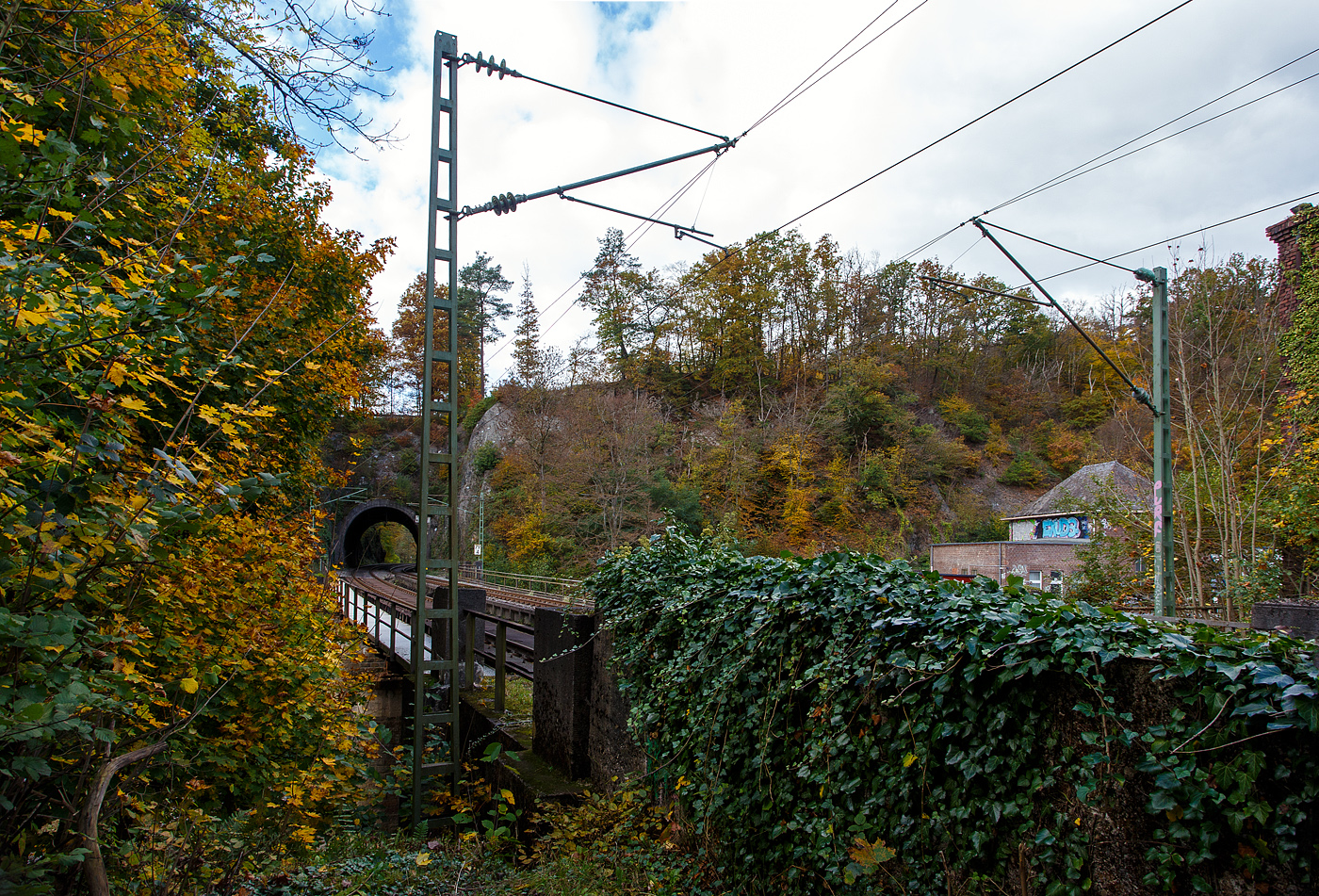 Blick und Durchblick auf/durch den 32 m lange Mühlburg-Tunnel bei km 74,4 der Siegstrecke (KBS 460) in Scheuerfeld/Sieg am 18 Oktober 2025. Davor die Brücke über die Sieg, bei der alten Papierfabrik ganz rechts, hier ist auch ein Siegwehr mit Wasserkraftwerk. Da die Sieg hier auch eine Schleife macht ist kurz hinter dem Tunnel wieder eine Brücke über die Sieg.

Die Siegstrecke ist eine rund 100 Kilometer lange, überwiegend zweigleisige, elektrifizierte Hauptbahn von Köln nach Siegen in Deutschland. Zwischen Blankenberg und Merten sowie zwischen Schladern und Rosbach wurde sie nach dem Zweiten Weltkrieg nur eingleisig wiederaufgebaut. Beide Endbahnhöfe liegen im Bundesland Nordrhein-Westfalen, rund 28 Kilometer verlaufen in Rheinland-Pfalz. Die Strecke führt ab dem Bahnhof Köln Messe/Deutz über Porz (Rhein), Troisdorf, Siegburg, Hennef (Sieg), Au (Sieg) und Betzdorf (Sieg) nach Siegen Hbf. Die Siegstrecke wurde ursprünglich als Teil der Deutz-Gießener Eisenbahn errichtet und ging nicht über Siegen, sondern verlief von Betzdorf (Sieg) weiter über Herdorf, Haiger und Dillenburg bis Gießen. 