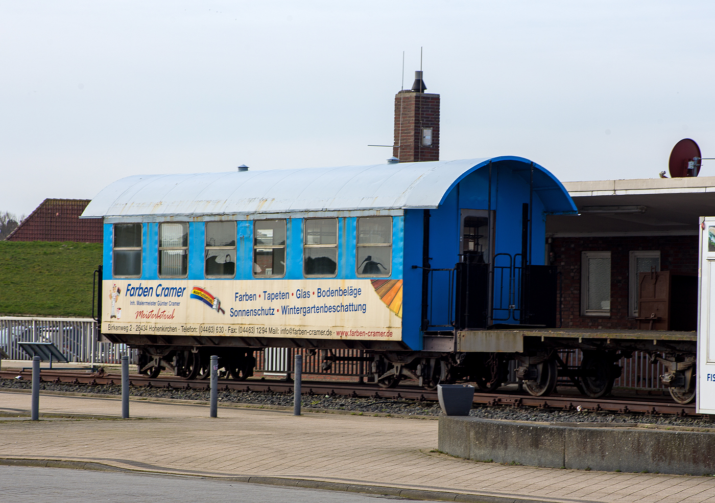 Der Denkmalwagen 63 109 ein vierachsiger schmalspuriger Drehgestell-Personenwagen mit zwei offenen Plattformen der 2. Wagenklasse DB 63109 der DB Fernverkehr AG (Wangerooger Inselbahn / SIW - Schifffahrt und Inselbahn Wangerooge) am 14 März 2024 beim Fährterminal (ehem. Bahnhof) Harlesiel. Rechts davor ein zweiachsiger unbekannter Flachwagen. 

Der Personenwagen wurde 1913 von der Düsseldorfer Eisenbahnbedarf AG, vorm. Carl Weyer & Cie. gebaut. Er war aber damals, für den raschen Fahrgastwechsel an den Anlegern, als Abteilwagen mit vielen Türen ausgeführt.

Lebenslauf:
1913 Auslieferung an GOE - Großherzoglich Oldenburgische Eisenbahnen als „Oldenburg 9“
01.04.1920 DR - Deutsche Reichseisenbahnen „Oldenburg 9“
31.08.1924 DRG - Deutsche Reichsbahn-Gesellschaft „Old 9“
01.01.1935 Umzeichnung in „Mst 9“
02.02.1937 DRB - Deutsche Reichsbahn „Mst 9“
1945 Abstellung, da schadhaft (ggf. d. Bombenangriff), Wagenkaten nicht wiederherstellbar.
07.09.1949 DB - Deutsche Bundesbahn „Mst 9“
31.12.1949 Ausmusterung
31.05.1950 Umbau durch BW Wangerooge „Mst 9“
Entfernung der beschädigten Seitenwände, Dachreparatur, neue Holzsitze. Nutzung als offener Sommerwagen. 
14.11.1955 Umzeichnung in „Mst 18“
1956 z-Stellung
1959 Umbau durch das AW Limburg (Lahn)
Neuaufbau des Wagenkastens (in die heutige Form) mit Teilen des laufenden yg-Umbauwagenprograms. Umzeichnung wieder in DB „Mst 9“
1965 Umzeichnung in „Mst 109“
01.04.1972 Umzeichnung in „Han109“ 
1988  Umzeichnung in DB 63 109
1992 Abstellung (Überführung ins Raw Wittenberge)
1997 Aufstellung als Denkmal in Harlesiel
2007 Äußerliche Aufarbeitung in der aktuellen Farbgebung der Inselbahn
2008 Innerliche Aufarbeitung im aktuellen Design der Schiffe. 2 ½ Reihen der Sitzbänke sind erhalten geblieben, der übrige Bereich dient als Besprechungsraum für 8 bis 10 Personen.

TECHNISCHE DATEN:
Spurweite:  1.000 mm (Meterspur)
Anzahl der Achsen: 4 (2´2´)
Länge über Puffer: 12.100 mm
Drehzapfenabstand: 7.500 mm
Achsabstand: im Drehgestell: 1.300 mm
Breite: 2.650 mm
Höhe: 3.565 mm
Sitzplätze (vor Umbau): 48
