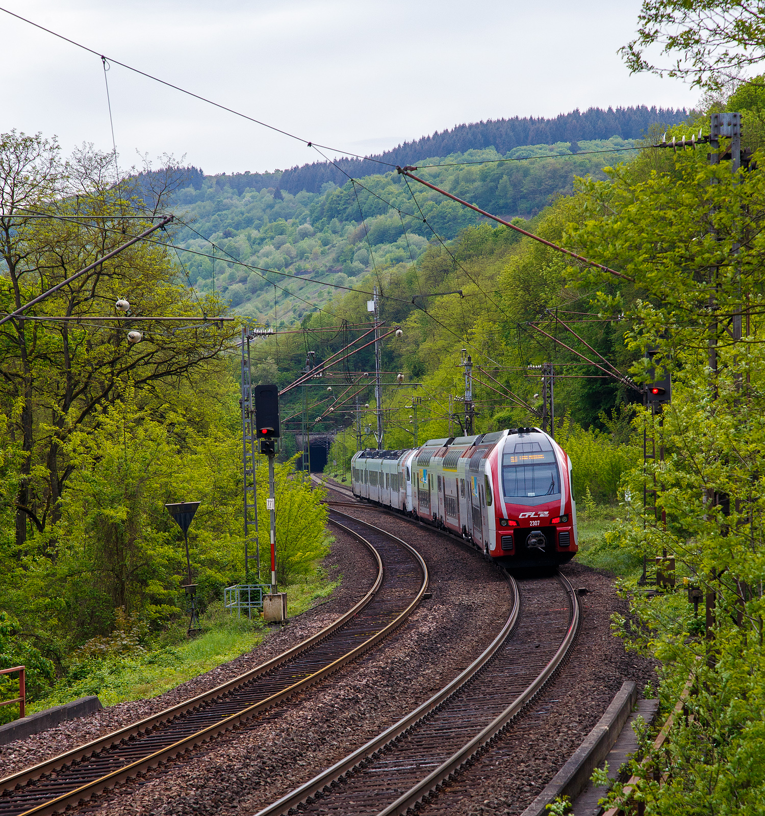 Der fünfteilige SÜWEX Stadler FLIRT³  - 429 110 / 429 610 als RE 1  Südwest-Express  gekuppelt mit dem dreiteiligen CFL Stadler KISS 2307 als RE 11  DeLux-Express  haben am 29.04.2018 gerade den Pündericher Hangviadukt verlassen und fahren weiter in Richtung Trier. Hinten folgt gleich dann der 504 m lange Reilerhals-Tunnel. Dazwischen kann man gut nach links den Abzweig auf die Moselweinbahn (KBS 691) nach Traben-Trarbach erkennen.

Der Stadler FLIRT³ fährt als RE 1 “Südwest-Express“ die Verbindung Koblenz – Cochem –Trier – Dillingen – Saarbrücken, teilweise fährt der RE 1 auch über Kaiserslautern bis Mannheim. Der CFL Stadler KISS fährt als RE 11  DeLux-Express  die Verbindung Koblenz – Cochem –Trier – Igel – Wasserbillig – Luxembourg. Im Hbf Trier werden die Triebzüge geflügelt (getrennt bzw. in Gegenrichtung gekuppelt).

Seit dem 16. März 2015 fahren die CFL-KISS auf dem Abschnitt zwischen Koblenz und Trier, auf der Moselstrecke (KBS 690), gemeinsam mit den FLIRT³  der DB Regio Südwest in gemischter Mehrfachtraktion. Das ein- und zweistöckige elektrische Triebzüge zweier Staatsbahnen gemeinsam unterwegs sind, dürfte europaweit einmalig sei. Ab dem 10.12.2017 fahren einzelne CFL KISS von Koblenz weiter über Bonn und Köln Hbf bis nach Düsseldorf.