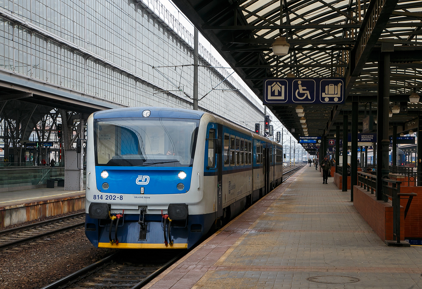 Der RegioNova „Trio“ 814 201-0 / 014 0xx / 814 202-9 steht am 23.11.2022 als Regionalzug im Hauptbahnhof Prag (Praha hlavn� n�dra��) zur Abfahrt bereit.

Diese dreiteiligen Fahrzeuge der ČD-Baureihe 814.2/014/814.2 entstanden im Rahmen eines Rekonstruktionsprogrammes (2007 bis 2012) aus den Fahrzeugen der ČD-Baureihe 810 bzw. Beiwagen der Reihe 010. Von den ČD werden sie als „RegioNova“ vermarktet.Der Einsatz des Fahrzeuges ergibt vor allem Energieeinsparungen, eine h�here Traktionsgeschwindigkeit und dadurch eine Straffung der Fahrpl�ne. 

Die Baureihe 814.2:
Eine Weiterentwicklung der Baureihe 814.0 ist die Baureihe 814.2. Eine Einheit besteht anstatt aus einem Motor- und einem Steuerwagen aus zwei Motorwagen (BR 814.2) und einem Mittelwagen (BR 014). Die dreiteiligen Z�ge bieten 127 Sitzpl�tze anstatt bei den zweiteiligen Wagen 76. Triebwagen der Baureihe 814.2 sind seit 2007 im Einsatz.

Technische Merkmale:
Wesentliche Ver�nderungen gegen�ber der Ursprungsbauart sind eine neue, leistungsf�higere Antriebsanlage mit dem Dieselmotor LIAZ ML 640 SE (TEDOM TD 242 RH TA25) und dem hydromechanischen Getriebe VOITH DIWA 864.3E, eine bequemere Innenausstattung mit behindertengerechter Toilette, bessere Arbeitsbedingungen f�r den Lokf�hrer, bessere Fahreigenschaften und geringere Umweltauswirkungen der Antriebsanlage. Die Regionova sind nach wie vor mit Schraubenkupplung ausger�stet und somit mit anderen Fahrzeugen freiz�gig kuppelbar.

Im Mittelwagen (BR 014), der zwischen den Rads�tzen einen Niederflurbereich auf etwa 50 % der Wagenl�nge aufweist, befinden sich das Traglastenabteil, eine Auffahrrampe f�r Rollst�hle, die Toilette und 31 Sitzpl�tze. Der Einstieg liegt in diesem Bereich in Wagenmitte. Der Triebwagen, in normaler Bodenh�he aufgebaut, besitzt Fahrgastabteile mit 48 Sitzpl�tzen. Die Antriebsanlage liegt wie bei der Ursprungsbauart unter dem Wagenboden, auch die Lage der Einstiege wurde bei den Triebwagen nicht ver�ndert.

Beschreibung von �koda:
Die Zuggarnituren entstehen durch eine Rekonstruktionen und Modernisierung der urspr�nglichen Wagen, die in den Jahren 1973-1983 hergestellt wurden. Der Hauptbeitrag der Rekonstruktion ist neben der Erh�hung der Qualit�t des Reisens auf den Regionalstrecken auch die Reduzierung der Kosten f�r den Betrieb und die Wartung.

Die modernisierten Einheiten haben einen geringeren Verbrauch und in den Endstationen m�ssen sie nicht umgespannt werden. Der Zug Regionova  Trio  besteht aus zwei Triebwagen und einem Niederflur-Zwischenwagen, der die Bef�rderung von Personen mit eingeschr�nkter Mobilit�t und von Eltern mit Kinderwagen erleichtert.. In den Zuggarnituren ist gen�gend Platz auch f�r gr��eres Gep�ck. Eine komplette Modernisierung machte auch der Zugf�hrerraum durch.

TECHNISCHE DATEN Regionova „Trio“:
Hersteller (Umbau): Pars Nova in �umperk (geh�rt zu �koda)
Spurweite: 1.435 mm (Normalspur)
Achsformel: 1'A' + 1'1' + A'1'
L�nge �ber Puffer: 42.410 mm
Wagenkastenbreite: 3.073 mm
H�he: 3.420 mm
Leergewicht: 62,3 t
Radsatzfahrmasse: 9,75 t
H�chstgeschwindigkeit: 80 km/h
Installierte Leistung: 242 kW (bei 1.950 U/min)
Anfahrzugkraft: 54 kN
Motorentyp: 2x TEDOM TD 242 RH TA25 (LIAZ ML 640 SE)
Getriebe: 2 x Voith Diwa 864.3E
Leistungs�bertragung: hydromechanisch
Sitzpl�tze: 127
Fu�bodenh�he: 570 mm (Niederflurteil)
Kleinster befahrbarer Gleisbogen: R 120 m
Bremse: DK-P

