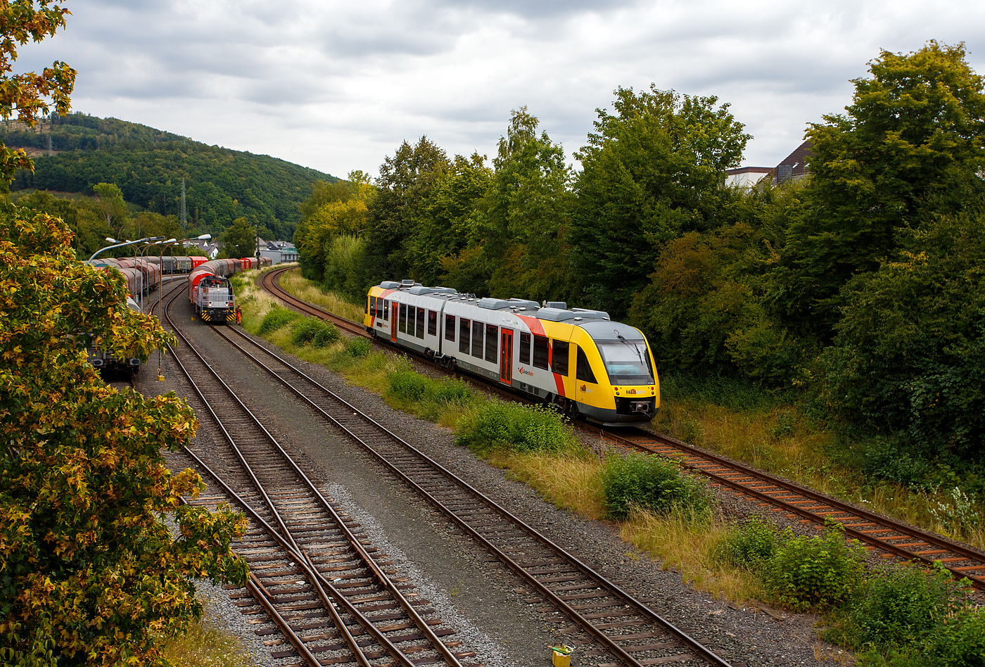 Der VT 253 (95 80 0648 153-4 D-HEB / 95 80 0648 653-3 D-HEB) ein Alstom Coradia LINT 41 der HLB (Hessische Landesbahn) hat am 22 August 2025, als RB 96 „Hellertalbahn“ (Betzdorf – Herdorf – Dillenburg, den Bahnhof Herdorf verlassen und fährt weiter in Richtung Neunkirchen/Siegerland.

Links steht die KSW 42 bzw. 277 902-3 (92 80 1277 902-3 D-KSW) der KSW (Kreisbahn Siegen-Wittgenstein) mit einem Übergabegüterzug auf den KSW Rangierbahnhof Herdorf (Freien Grunder Eisenbahn KSW NE447 / DB-Nr. 9275) zur Abfahrt bereit. Kurzdrauf wird sie mit dem Übergabegüterzug via Betzdorf/Sieg und Siegen nach Kreuztal losfahren. 

Es ist für die nächsten 3 Wochen die letzte Fuhre über die KBS 460 „Siegstrecke“ nach Kreuztal, da die Strecke zwischen Siegen und Troisdorf wegen Bauarbeiten dann gesperrt ist. Dann muss die KSW über Haiger nach Dillenburg fahren und nach dem Umsetzen dort über die KBS 445 „Dillstecke“ nach Kreuztal. Da die Wagen dann leer sind ist nur der Umweg von Nachteil, nicht aber die geringere Streckenklasse CE zwischen Herdorf und Haiger. 