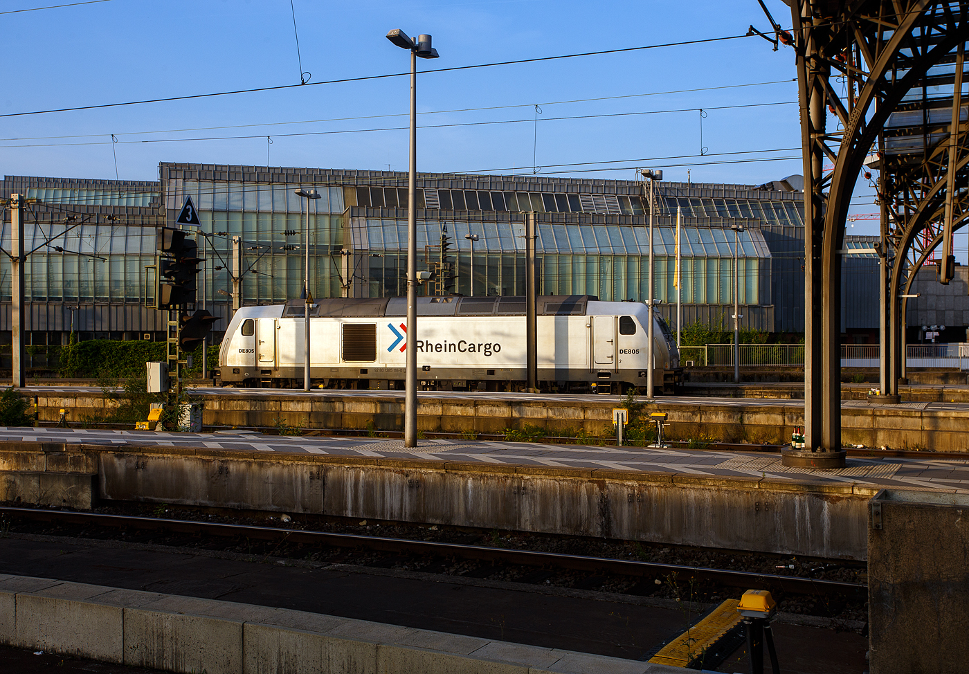 Die 285 116-0/DE 805 (92 80 1285 116-0 D-RHC) der RheinCargo fährt am frühen Morgen des 18 Juni 2025 (6:43 Uhr), auf Tfzf (Triebfahrzeugfahrt) durch den Hauptbahnhof Köln, in Richtung Deutz. 

Die TRAXX F140 DE wurde 2013 von der Bombardier Transportation GmbH in Kassel unter der Fabriknummer 34995 gebaut und als  76 107  - 92 88 0076 107-6 B-BTK an die BTK Bombardier Transportation GmbH (Kassel) geliefert bzw. eingelagert. Sie war wohl wie vier weitere für einen anderen Kunden vorgesehen. Im Herbst 2013 übernahm der Betreiber RheinCargo aus Neuss die Lieferung der fünf eingelagerten neuen Traxx F140 DE Lokomotiven (76 103-107). Die ersten drei Loks (ex 76 103, 104 und 105) wurden am 01.10.2013 zu den ex HGK-Werkstätten (HGK ist heute Teil der RheinCargo) in Brühl-Vochemon transportiert. Nach einigen Tests und neuen Rheincargo-Logos wurden die drei Maschinen am 21.11.2013 offiziell vorgestellt. Die wurde im Dezember 2013 von der RheinCargo gekauft. Die Lok hat die Zulassungen für Deutschland, Belgien und die Niederlande

Die Lokomotiven TRAXX F140 DE sind die aus der Plattform Traxx 2e des Herstellers Bombardier hervorgegangene Mehrzweck-Dieselversion. Sie sind mit einem 2.200 kW (3.000 PS) starken MTU 16V 4000 R41L Dieselmotor und elektrischer Wechselstrom-Kraftübertragung ausgestattet, so dass sie eine Anfahrzugkraft von 270 kN und eine maximale Betriebsgeschwindigkeit von 140 km/h erreicht. Diese Lokomotiven sind beliebt bei Unternehmern, die elektrische Traxx-Flotten im Betrieb haben, aber für Strecken mit langen, nicht elektrifizierten Abschnitten zuverlässige Zugkraft brauchen.

TECHNISCHE DATEN der BR 285 (TRAXX F140 DE):
Hersteller: Bombardier Transportation
Baujahre: 2007 bis 2013 (35 Stück)
Spurweite: 1.435 mm
Profil: UIC 505-1
Achsfolge: Bo´Bo´
Länge über Puffer: 18.900 mm
Drehzapfenabstand: 10.440 mm (virtuell)
Achsabstand im Drehgestell: 2.600 mm
Treibraddurchmesser: 1.250 mm (neu) / 1.170 mm (abgenutzt)
Breite: 2.977 mm
Höhe: 4.264 mm
Dienstgewicht: 82 t
Maximale Geschwindigkeit: 140 km/h
Anfahrzugkraft: 270 kN
Dauerzugkraft: 240 kN ab 26 km/h

Dieselmotor Hersteller: Motoren- und Turbinen-Union, Friedrichshafen (MTU)
Dieselmotor Art/Typ: wassergekühlter V-16-Zylinder- 4Takt-Dieselmotor mit zweistufiger Turboaufladung und Ladeluftkühlung, sowie mit Common-Rail-Einspritzsystem vom Typ MTU 16V 4000 R41L
Der Motor schaltet im Leerlauf 8 der 16 Zylinder ab, um den Spritverbrauch und Schadstoffausstoß zu senken.
Motor-Hubraum: 76,265 l (Bohrung 170 mm, Hub 210 mm)
Motorgewicht: 7.930 kg (trocken) / 8.510 kg (nass)
Dieselmotorleistung: 2.200 kW (3.000 PS) bei 1.800 U/min

Kraftübertragung: dieselelektrisch
Traktionsmotoren:  4 Stück Drehstrom-Asynchronmotor
Leistung am Rad: 1.825 kW
Antrieb: Tatzlagerantrieb
Bremskraft: 150 kN
Elektrische Bremsleistung: max. 1.000 kW
Tankvolumen: 5.000 l 
Bauart der Bremsen: Druckluftbremse, Feststellbremse, Dynamische Bremse
Kleister befahrbarer Gleisbogen: R = 100 m
Zugsicherung: GSM-R, PZB90 
Bremsgewicht: P 90 G 77
