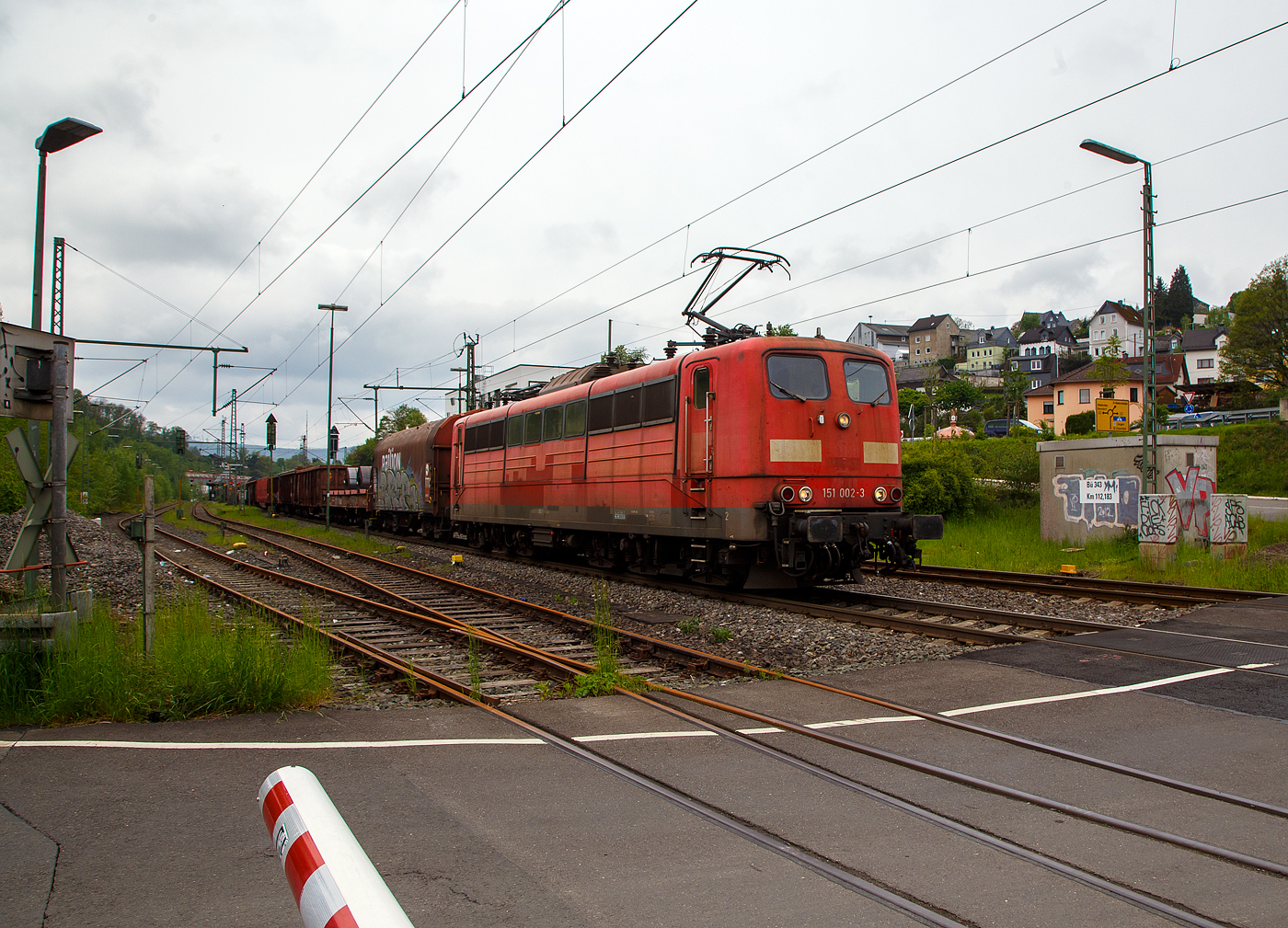 Die an die DB Cargo AG vermietete Railpool 151 002-3 (91 80 6151 002-3 D- Rpool) f�hrt mit einem gemischten G�terzug am 11.05.2023 durch Niederschelden (hier beim B� 343 – km 112,183 der Siegstrecke) in Richtung Siegen.

Die Lok wurde 1973 von Krupp in Essen unter der Fabriknummer 5174, der elektrische Teil ist von AEG unter Fabriknummer 8820, gebaut, und an die Deutsche Bundesbahn geliefert. Bis zum 31.12.2016 geh�rte sie zur DB Cargo AG. Zum 01.01.2017 wurden je 100 sechsachsige elektrische Altbau-Lokomotiven der Baureihen 151 und 155 an ein Konsortium aus dem Lokvermieter Railpool verkauft. Die DB Cargo mietet daraufhin 100 Loks von Railpool wieder an. Die anderen Maschinen werden dem freien Markt angeboten.

Diese sechsachsigen Loks (Co’Co’) sind immer noch starke Zugpferde, und so manche moderne Lok hat nicht diese Leistungsf�higkeit. Mit einer Stundenleistung von 6.288 kW (8.550 PS) bei 92 km/h und einer Anfahrzugkraft von 395 kN k�nnen diese Loks 3.000 t Z�ge bei 3 ‰ Steigung noch mit einer Dauergeschwindigkeit 75 km/h ziehen, bei 2.000 t Z�gen sind es 100 km/h.