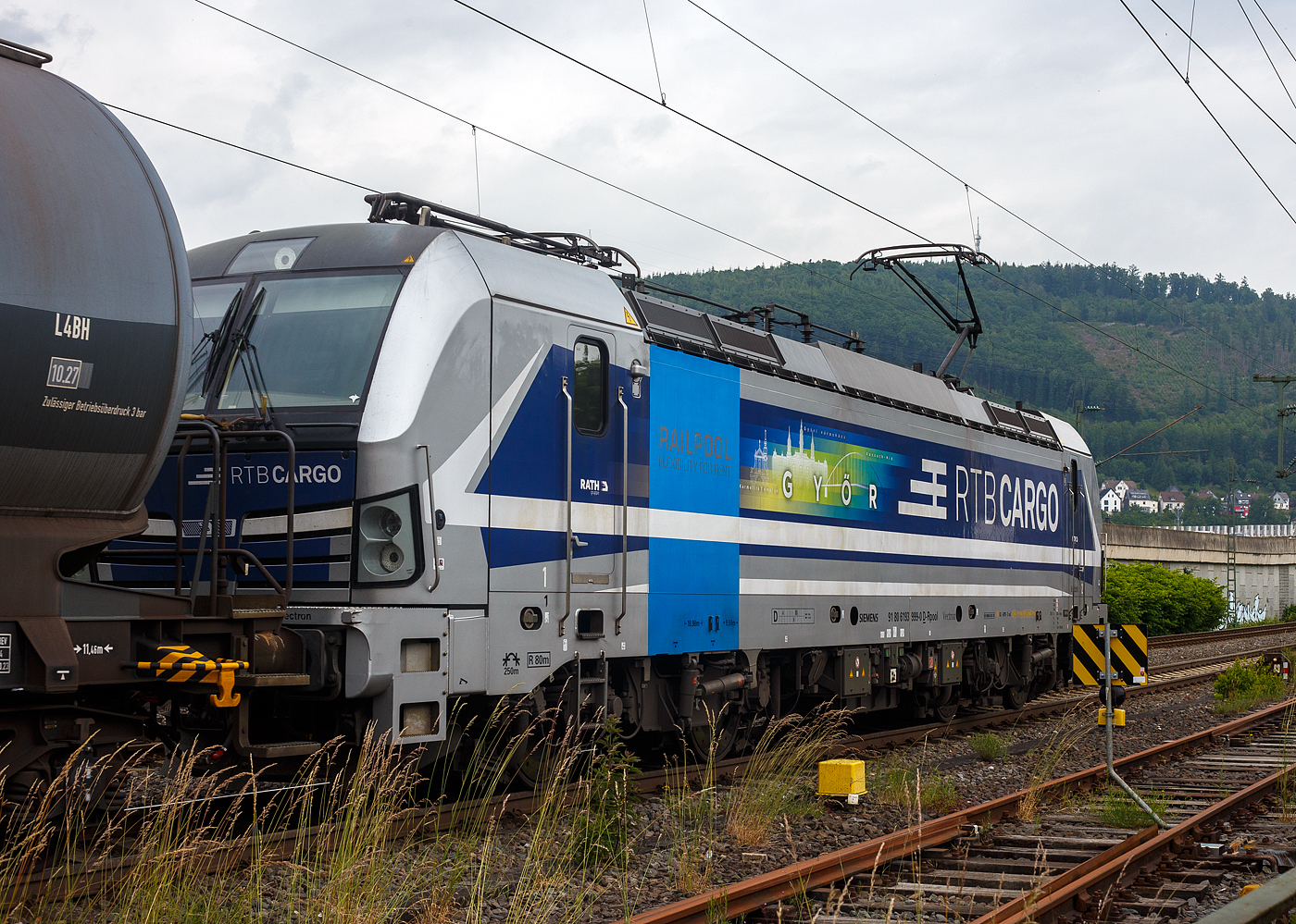 Die an die RTB Cargo - Rurtalbahn Cargo GmbH (RATH Gruppe) vermietete SIEMENS Vectron AC 193 999-0 „Győr“ (91 80 6193 999-0 D-Rpool) fährt am 10 Juni 2025 mit einem, laut Warntafel (30/1202) mit Heizöl oder Diesel beladenen, Kesselwagenzug durch Niederschelderhütte in Richtung Siegen 

Die Wechselstromlok (AC 15 kV 16,7 Hz und AC 25 kV 50 Hz) SIEMENS Vectron AC 193 999-0 wurde 2019 von Siemens Mobilitiy in München-Allach unter der Fabriknummer 22698. Sie ist als Vectron AC B16-2b ausgeführt und hat so die Zulassung für Deutschland, Österreich, Ungarn und Rumänien (D / A / H + RO). Sie hat eine Leistung von 6.400 kW (8.700 PS). 