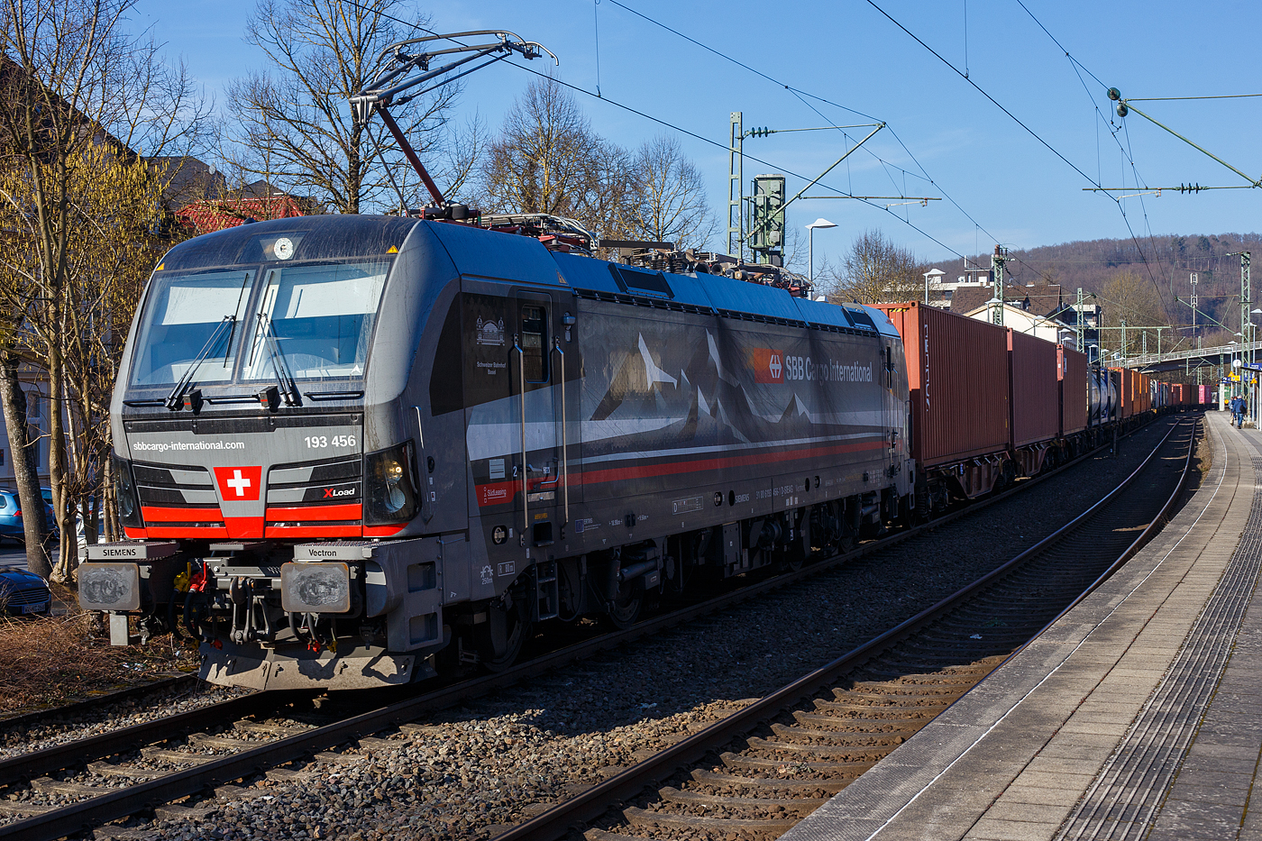 Die an die SBB Cargo International AG vermietete mit „XLoad“ ausgestattete 193 456  Schweizer Bahnhof Basel  (91 80 6193 456-1 D-SIEAG) der S�dLeasing GmbH, Stuttgart (eingestellt in Deutschland durch Siemens) f�hrt am 18 Februar 2025 mit einem KLV-Zug, durch Kirchen (Sieg) in Richtung K�ln.

Die Multisystemlokomotive Siemens Vectron MS wurde 2024 von Siemens Mobilitiy in M�nchen-Allach unter der Fabriknummer 23784 gebaut und am 12.09.2024 ausgeliefert. Sie wurde in der Variante A40-1a ausgef�hrt und hat so die Zulassung f�r Deutschland, �sterreich, die Schweiz, Italien, die Niederlande und Belgien (D / A / CH / I / NL / B). Sie verf�gt �ber eine Leistung von 6,4 MW (160 km/h) und ist neben den nationalen Zugsicherungssystemen mit dem Europ�ischen Zugsicherungssystem (ETCS BL3) ausgestattet. Zudem ist sie mit der neuen Ausr�stungspaket XLoad ausgestattet. 

Das neue XLoad Ausr�stungspaket f�r Vectron:
XLoad ist ein Ausr�stungspaket f�r Vectron, welches k�nftig mitbestellt, aber auch bei bereits ausgelieferten Vectron Loks nachger�stet werden kann. Das Feature verbessert die Reibwertausnutzung und erm�glicht dadurch h�here Anh�ngelasten. Zudem reduzieren die Fahreigenschaften, die das Feature bewirken, den Verschlei� von Rad und Schiene.

Aktuell sind die Schweizer Vectron-Lokomotiven (SBB Cargo und BLS Cargo) in der Regel in Doppeltraktion unterwegs. Die Steigungen und Rampen der Schweizer Berge sind vor allem bei schlechten Witterungsbedingungen nicht ohne. Eine Lokomotive muss auch bei geringerem Schlupf gen�gend Traktion auf die Schienen bringen, um alle G�ter sicher und zuverl�ssig ans Ziel zu bringen. Ein effizienter Weg aus dieser �Misere� ist die f�r Vectron entwickelte Zusatz-Funktion �XLoad�. Den erfolgreichen Beweis trat eine SIEMENS Testlokomotive im Fr�hjahr 2022 bei der SBB Cargo International und bei der BLS Cargo eindr�cklich an. 

F�r SBB Cargo International bewies die Test-Lokomotive am B�zberg und f�r BLS Cargo an der Nordrampe des L�tschbergs ihre enorme Zugkraft. 
Vectron meisterte im Fr�hjahr 2022 die lange 12‰-Steigung des B�zbergs mit einer Anh�ngerlast von 2.000 Tonnen bravour�s. Bei den n�chtlichen Testfahrten zeigte sich eindr�cklich die enorme Zugkraft der Lokomotive. 

Am L�tschberg wurden bei der BLS Cargo steigungsm��ig noch ein paar Promille draufgepackt. Mit 1.020 Tonnen im Gep�ck bew�ltigte die Vectron-Lokomotive mit XLoad-Feature die 27‰-Steigung der Nordrampe ebenfalls meisterlich. Und auch diverse Anfahrtsversuche absolvierte der mit dem XLoad-Feature aufger�stete Vectron problemlos. 

So bestellte die S�dLeasing GmbH (Stuttgart) im Auftrag der SBB Cargo International j�ngst 20 Vectron Lokomotiven mit XLoad bei SIEMENS.