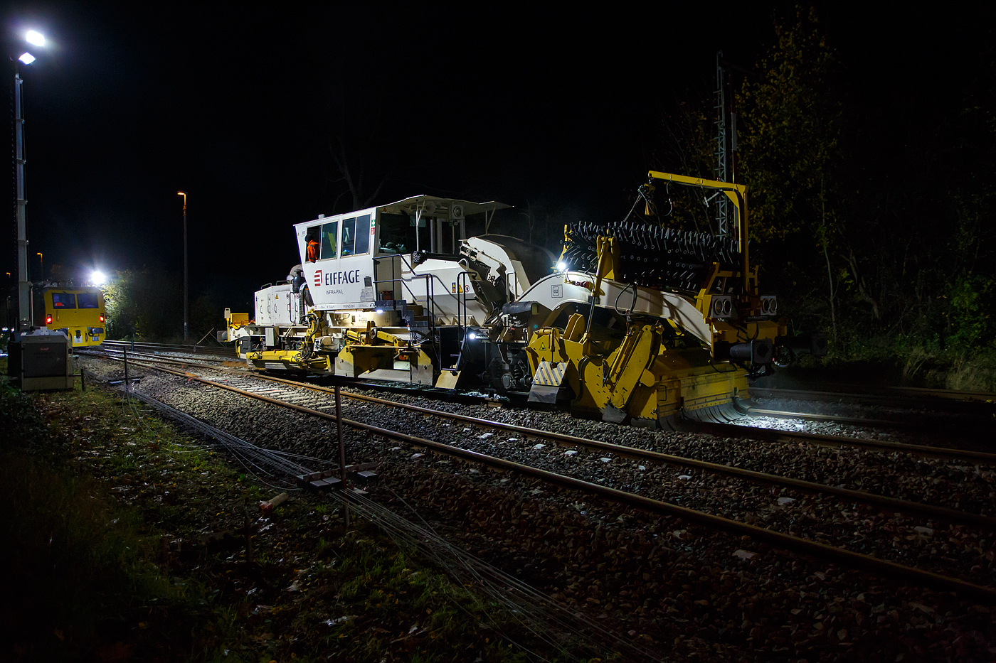 Die Baustelle Bahnhof Herdorf am Abend des 26 Oktober 2025 (ab 21:10 Uhr). Nach jedem Stopfdurchgang, wie hier von der P & T UNIMAT 09-4x4/4S E� (eine Nivelier-, Hebe-, Richt- und Universalstopfmaschine), der neuen Weiche 3 folgt eine Schotterplaniermaschine. So ist es hier die Schnell-Schotterplaniermaschine SSP 110 SW, D-ERB 99 80 9425 039-1 der Eiffage Infra-Rail GmbH (Herne), ex 97 16 40 546 17-4 der Heitkamp GmbH Herne (sp�ter Eiffage Rail), im Einsatz.

Der Schotterpflug wurde 1995 von der Deutschen Plasser unter der Fabriknummer 591 gebaut. 

TECHNISCEN DEATEN der Schotterplaniermaschine SSP 110 SW:
Spurweite: 1.435 mm (Normalspur)
Achsanzahl: 2
L�nge �ber Puffer: 17.230 mm
Achsabstand: 8.100 mm
Eigengewicht: 37 t
Anh�ngelast: 20 t
H�chstgeschwindigkeit: 90 km/h
Zugelassen zur Mitfahrt:  3 Personen
Kleinster befahrbarer Kurvenradius:  R 120 m      
Zugelassen f�r Streckenklasse: B1 und h�her