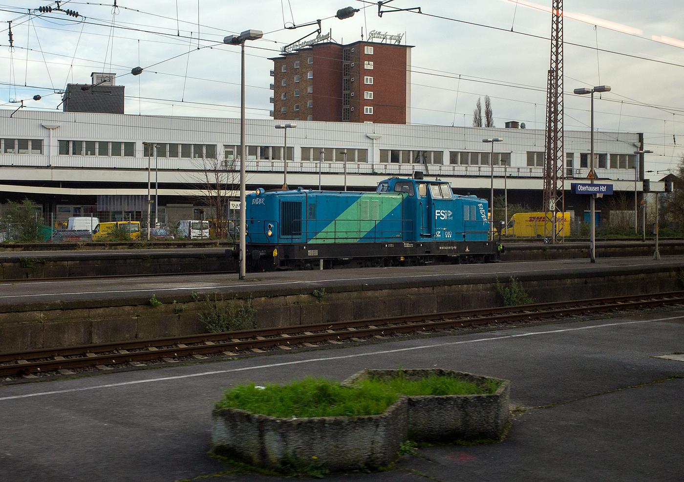 Die Deutz DG 1200 BBM - 423 001-7 „Ender“ (98 80 3423 001-7 D-FSI) der FSI Logistik GmbH (Teil der AY Holding GmbH) kommt unserem ICE (aus diesem fotografiert) am 14 M�rz 2014 entgegen im Hauptbahnhof Oberhausen entgegen. 

Ein Jahr nach der Einf�hrung der 1.000 PS-Lok DG 1000 BBM stand ein leistungsst�rkerer Motor zur Verf�gung, so dass jetzt mit der DG 1200 BBM nochmal 200 PS mehr an Traktionsleistung angeboten werden konnten. So wurde diese Lok als erste dieses Typs 1960 von Deutz unter der Fabrik-Nr. 57100 gebaut und an die OHE - Osthannoversche Eisenbahnen AG in Celle als OHE 120071 geliefert. Im April 1960 wurde sie auf der Deutschen Industriemesse Hannover pr�sentiert. Der damalige Kaufpreis betrug 495.000 DM. In den 1990er-Jahren erhielt die Lok in der Hauptwerkstatt OHE - Osthannoversche Eisenbahnen AG einen Umbau und die Remotorisierung mit dem heutigen Motor vom Typ MTU 12V396TC12. 

2007 bekam sie vom EBA die NVR-Nummer  98 80 3423 001-7 D-OHE, im August 2012 wechselte sie in Cargo Sparte (OHE Cargo GmbH) und bekam die UIC-Nummer 98 80 3423 001-7 D-OHEGO. Im Dezember 2016 ging sie an Talbot Services GmbH in Aachen als 98 80 3423 001-7 D-TAL und 2022 wurde sie an die FSI Logistik GmbH verkauft.

Die KHD DG 1200 BBM ist eine Vierachsige Diesellokomotive mit der Achsfolge B'B', von ihr wurden 18 Exemplare von 1960 bis 1966 gebaut. Die DG 1200 BBM war die leistungsst�rkste Lokomotive des Deutz-Typenprogramms 1959. Sie stellt eine verst�rkte Version der DG 1000 BBM dar. 

Jeweils vier Loks sind in die Niederlande und nach Italien verkauft worden. Eine Lok wurde verschrottet.

TECHNISCH DATEN:
Spurweite: 1.435 mm (Normalspur)
Achsformel: B'B'
L�nge �ber Puffer: 13.500 mm
Dienstgewicht: 80 t
H�chstgeschwindigkeit: 70 km/h
Urspr�nglich verbauter Motor: Deutz wassergek�hlter V-Zw�lfzylinder-Zweitakt-Dieselmotor mit Direkteinspritzung vom Typ KHD BT12M625. Der Motor hatte eine Zylinderbohrung von 200 mm und einen Kolbenhub von 250 mm. Damit hatte der Motor einen Hubraum von 94,2 l.

Heute verbauter Motor: Wassergek�hlter V-Zw�lfzylinder-Viertakt-Dieselmotor  mit Turboaufladung und Ladeluftk�hlung, sowie mit Direkteinspritzung , vom Typ MTU 12V 396 TC 12. Der Motor hat ein Zylinderbohrung von 165 mm und einen Kolbenhub von185 mm. Damit hat der Motor einen Hubraum von 47,5 l.
Installierte Leistung: 880 kW (1.200 PS)
Getriebe: Voith L306r

Die Typenbezeichnung   DG 1200 BBM   bedeutet:
D - Gro�diesellok
G - Kraft�bertragung �ber Gelenkwelle
1 2 0 0	- Motorleistung (rund 1200 PS)
B B - Achsfolge (Lok mit Drehgestell mit je zwei Achsen)
M - Mittelf�hrerhaus
