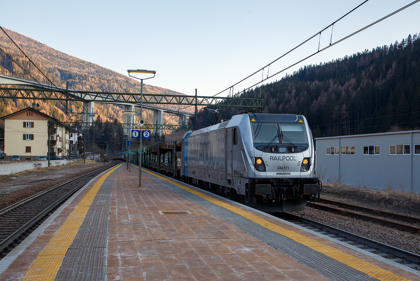 Die Railpool 494 571 (91 83 2494 571-9 I-RPOOL), eine Bombardier TRAXX F140 DC3 LM (mit Last-Mile-Modul), fährt am späten Nachmittag des 27 März 2022 mit einem leeren Autozug der ARS Altmann AG durch den Bahnhof Gossensaß / Colle Isarco hinauf zum Brenner / Brennero. Im Hintergrund das Gossensaß-Viadukt (Viadotto Colle Isarco) der Brennerautobahn (Autostrada del Brennero / Autostrada A22).

Diese Gleichstromloks der italienischen Baureihe E 494.5, vom Typ Bombardier TRAXX F140 DC3 LM, sind mit einem 275 kW Dieselmotor (Last-Mile-Modul) ausgestattet, um Rangierfahrten innerhalb nicht elektrifizierter Rangierbahnhöfe durchführen zu können. Das Modul kann auch zur Selbstrettung im Falle einer Störung des elektrischen Traktionssystems verwendet werden.

Die für Einsätze in Italien, Polen und Slowenien entworfenen Lokomotiven, haben gleich wie die MS3-Variante wieder glatte Außenwände. Das Last-Mile-Modul, bestehend aus Dieselmotor, Traktionsbatterie und Kraftstofftank verfügbar. In Italien werden sie als Baureihe E.494 bezeichnet. Die Loks mit LM-Modul werden als BR E.494.5 geführt, Loks ohne LM werden als BR E.494.0 geführt.

Neue Lokomotive E.494 der TRAXX-Familie von Bombardier wird mit 3 kV Gleichstrom betrieben und ist für das italienische Eisenbahnnetz zugelassen. Mit einer Leistung von 6,4 MW und einer Höchstgeschwindigkeit von140 km/h hat es eine Zugkraft beim Anfahren von 320 kN. Ausgestattet mit elektrischer regenerativer und rheostatischer Bremse, SCMT-Signalisierung und Vorbereitung für ETCS.

TECHNISCHE DATEN:
Hersteller: Bombardier, Werk Vado Ligure (Italien)
Spurweite:  1.435 mm (Normalspur)
Achsformel: Bo'Bo'
Länge über Puffer: 18.900 mm
Höhe: 4.228 mm
Breite: 2.977 mm
Drehzapfenabstand:  10.440 mm
Dienstgewicht: 86 t
Höchstgeschwindigkeit: 140 km/h / bei LM 50 km/h 
Dauerleistung:  6.000 kW (6.400 kW boost)
Anfahrzugkraft:  300 kN (320 kN mit Booster)
Treibraddurchmesser:  1.250 mm (neu) / 1.170 mm (abgenutzt)
Stromsysteme: 3.000 V DC / 1.500 V DC
Anzahl der Fahrmotoren: 4 Asynchronmotoren