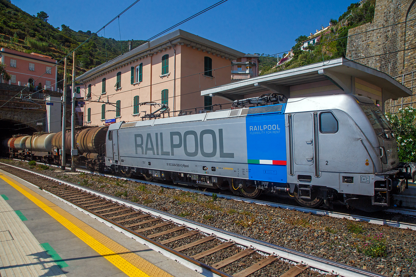 Die Railpool 494 580 (91 83 2494 580-0 I-RPOOL), eine Bombardier TRAXX F140 DC3 LM (mit Last-Mile-Modul), fährt am 22.07.2022 mit einem Kesselwagenzug durch den Bahnhof Riomaggiore (Cinque Terre) an der Italienischen Riviera in Richtung La Spezia bzw. Pisa. 

Riomaggiore ist das südlichste der fünf Dörfer der Cinque Terre (Fünf Ortschaften) und verfügt, wie die anderen Dörfer, über eine Eisenbahnstation an der Bahnstrecke Pisa–Genua (RFI Strecke-Nr. 77 / KBS 31 La Spezia–Genua), die den Ort mit den Nachbardörfern und mit La Spezia und Levanto verbindet. 