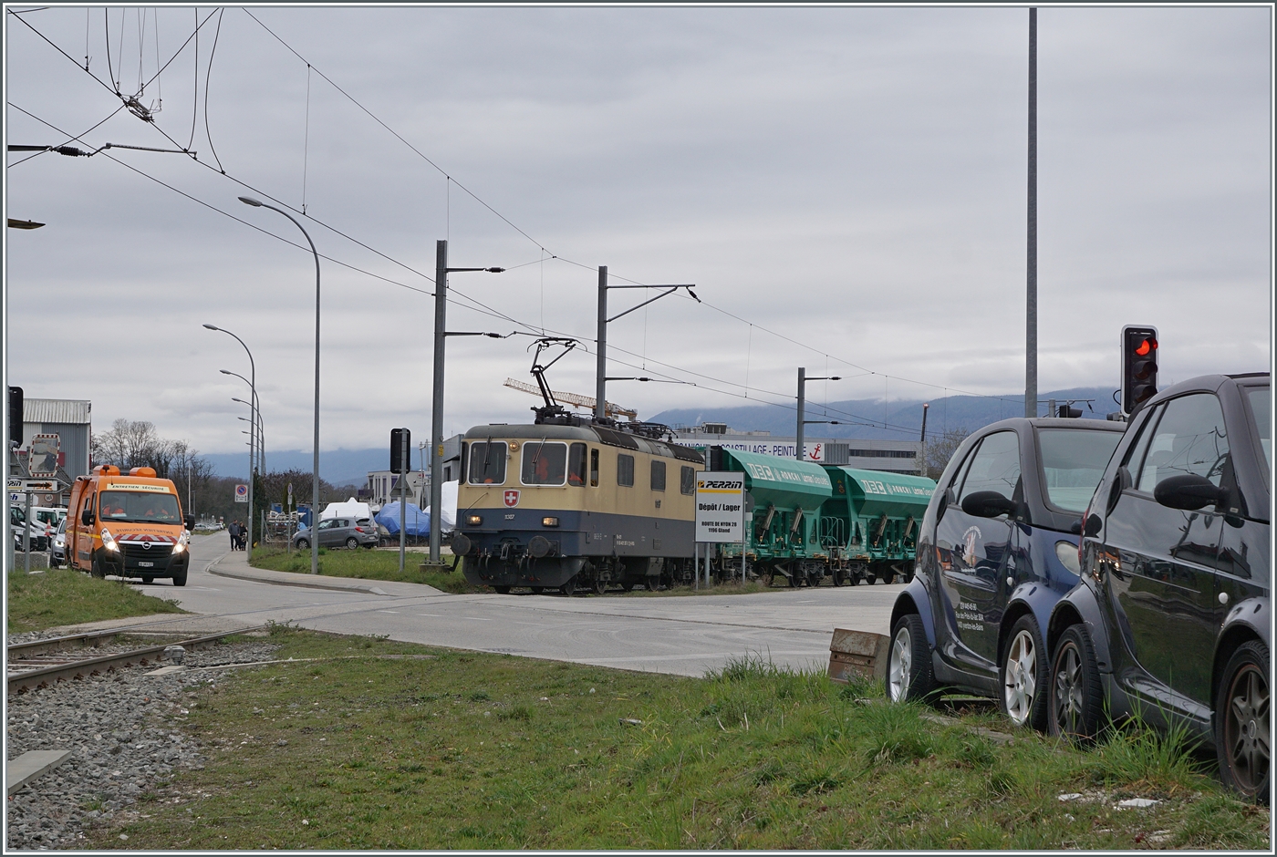Diese �bersichtsbild zeigt, dass ich beim vorherigen Bild NICHT mitten auf dem Gleis stand, sondern auf der Strasse, die zum Zeitpunkt der Aufnahme nicht f�r den Autoverkehr gesperrt war. Hier hingegen waren die Autos, damit die IRSI/IGE  Rheingold  Re 4/4 II 11387 (Re 421 387-2) mit ihrem Kieszug zum Bahnhof von Gland fahren kann (und dies mit sehr geringer Geschwindigkeit).

4. M�rz 2024