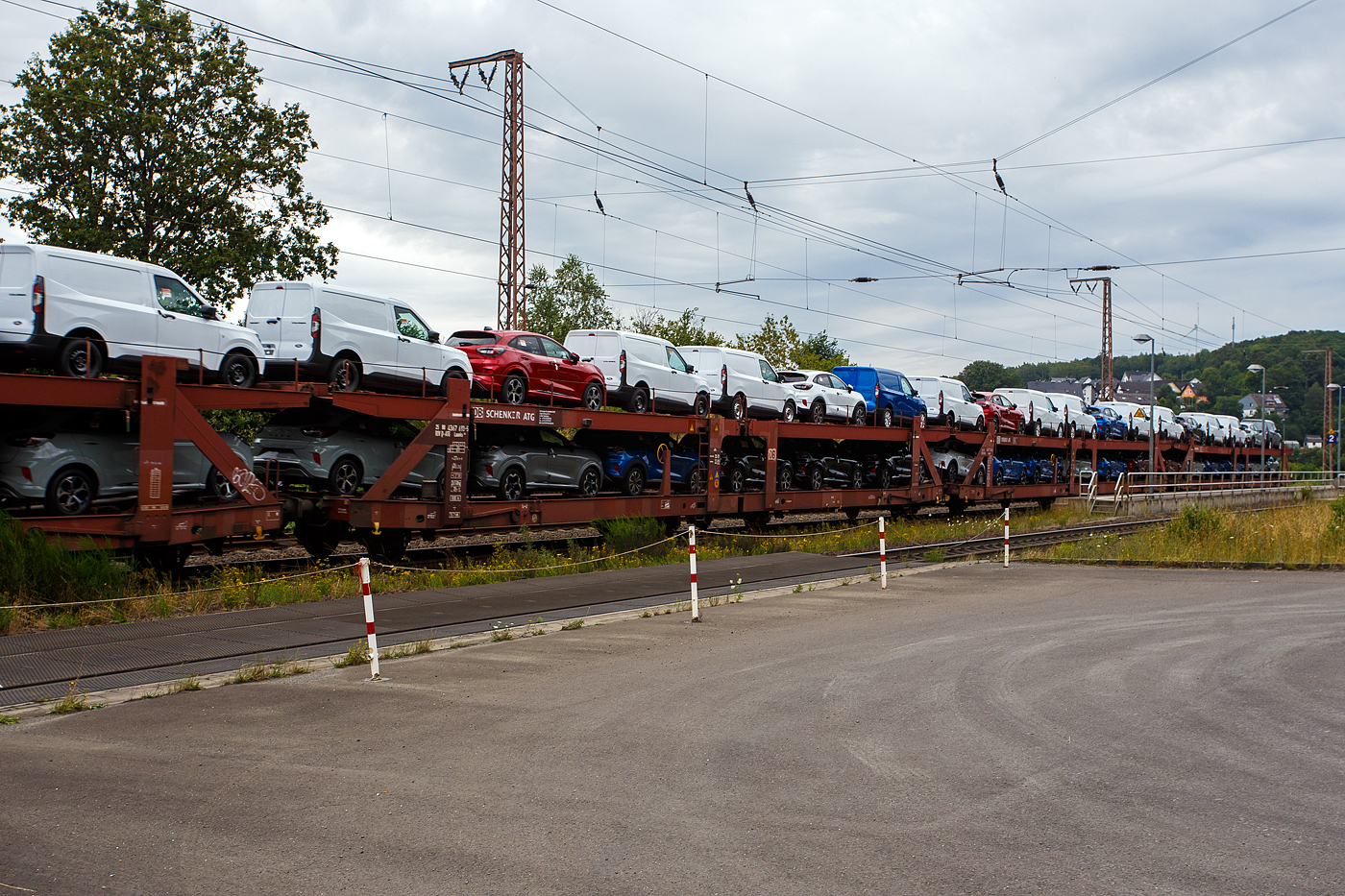 Doppelstock-Autotransportwagen 25 80 4367 693-5 D-ATG, der Gattung Laaeks 553, der DB Cargo Logistics GmbH (ex DB Schenker ATG) am 01 August 2024 im Zugverband bei der Zugdurchfahrt in Wilnsdorf-Rudersdorf (Kreis Siegen).

Der Wagen wurde 1988 von der Wagon Union (WU) in Berlin-Borsigwalde gebaut

Diese zuverlässigen und robusten Wagen dieser Bauarten wurden für den internationalen Transport von PKW entwickelt. Zur Be- und Entladung der oberen Ladeebene an Kopframpen können die Wagenenden aus der Transportstellung in die sogenannte Rampenstellung abgesenkt beziehungsweise angehoben werden. Des Weiteren können die Wagenenden der oberen Ladeebene in die Beladestellung angehoben werden. Hierdurch wird die maximale Durchfahrtshöhe für die Be- und Entladung der Fahrzeuge auf der unteren Ladeebene realisiert.

TECHNISCHE DATEN:
Gattung: Laaeks (Bauart 553)
Erstes Baujahr der Wagengattung: 1986
Spurweite: 1.435 mm
Anzahl der Achsen: 4
Länge über Puffer : 27.000 mm
Achsabstände: 9.000 / 4.300 / 9.000 mm
Ladelänge : 26.100 mm (unten) / 26.500 mm (oben)
Ladebreite : 3.000 mm (unten) / 2.910 mm (oben)
Wagenhöhe: 3.400 mm
Höchstgeschwindigkeit: 100 km/h (beladen) /120 km/h (leer)
Eigengewicht: 26.500 kg
Nutzlast: 18,5 t ab Streckenklasse A (unten max. 12 t / oben max. 10 t)
Kleinster befahrb. Gleisbogenhalbmesser: R = 80 m
Bremse: KE-GP (LL)
Bremssohle: IB 116
Intern. Verwendungsfähigkeit: RIV
