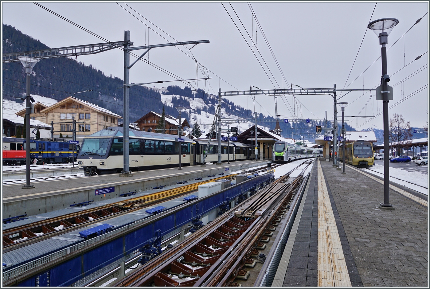 Faszination Spurwechsel: Im Vordergrund des Bildes sind die beiden Spurwechselanlagen in Zweisimmen zu sehen. Aufgabe dieser Einrichtung ist es, die Drehgestelle der umzuspurenden GPX Wagen zu entriegeln, umzuspuren und wieder zu verriegeln. Dabei werden die Drehgestelle der Schmalspurlok nicht touchiert. Normalspurige Fahrzeuge fahren durch die  nach unten geklappte  Umspuranlage, wie sie links zu sehen ist. Allen Ausf�hrungen zum Trotz habe ich nicht ganz nachvollziehen k�nne, wie die MOB Ge 4/4 Schmalspurlok �ber das Schmalspurschienlose Zwischenst�ck der Anlage kommt. Ich vermute, sie rollt allein auf den Spurkr�nzen. 

Im Hintergrund ist der aus Bern in Zweisimmen angekommen BLS RABe 528 107 zu sehen - und am Bahnsteig gleich gegen�ber der MOB Anschlusszug nach Montreux. Eine weiter und recht m�hsamen Wege haben hingegen die Reisenden nach der Lenk, sie m�ssen den Bahnsteig wechseln. Grund genug, von einem k�nftigen Konzept zu Tr�umen, welches st�ndliche Spurwechselz�ge von Bern nach der Lenk im Simmental anbietet...

15. Dezember 2022