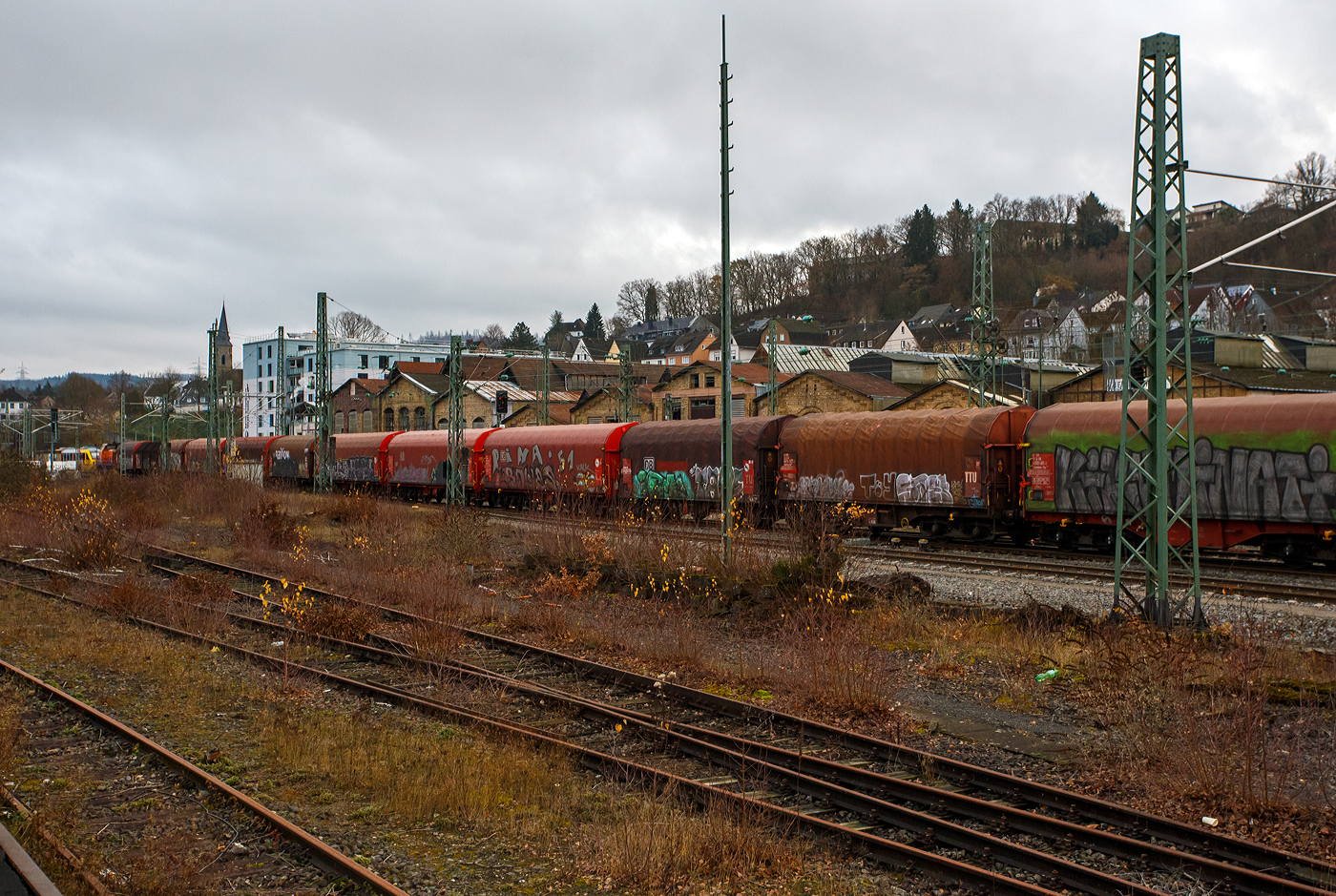 Geführt von der KSW 44 (92 80 1271 004-4 D-KSW), eine MaK G 1000 BB, fährt am 04 Dezember 2025 die KSW (Kreisbahn Siegen-Wittgenstein), im Sandwich mit einem sehr langen und schweren Coilzug, vom Rangierbahnhof Betzdorf/Sieg in Richtung Herdorf zum KSW-Rangierbahnhof (Betriebsstätte FGE - Freien Grunder Eisenbahn) nun los. Hinten (nicht im Bild) ist die nachschiebende KSW 42 bzw. 277 902-3 (92 80 1277 902-3 D-KSW) eine Vossloh MaK G 1700 BB. 

Die Fuhre geht ja über die, nicht elektrifizierte, eingleisige KBS 462 „Hellertalbahn“, da nur eine Güterverkehrsfahrt zwischen den Personenverkehr der RB 96 passt, fährt die KSW lieber eine lange Fuhre im Sandwich. Für eine Lok wäre die Anhängelast eines solchen langen beladenen Coilzuges zu hoch. In Herdorf auf dem Rangierbahnhof der KSW, werden Züge in mehren Teile aufgeteilt und gehen dann über die KSW eigene Strecke NE 447 (ehem. Freien Grunder Eisenbahn nach Neunkirchen-Salchendorf (ehemals Pfannenberger Einigkeit) zu den Produktionshallen der EMW Stahl Service GmbH, ein Geschäftsbereich der SCHÄFER WERKE Gruppe. 

Schon heute werden so dorthin über 300.000 Tonnen Stahl pro Jahr über die Schiene angeliefert, zukünftig sind sogar 600.000 Tonnen geplant.