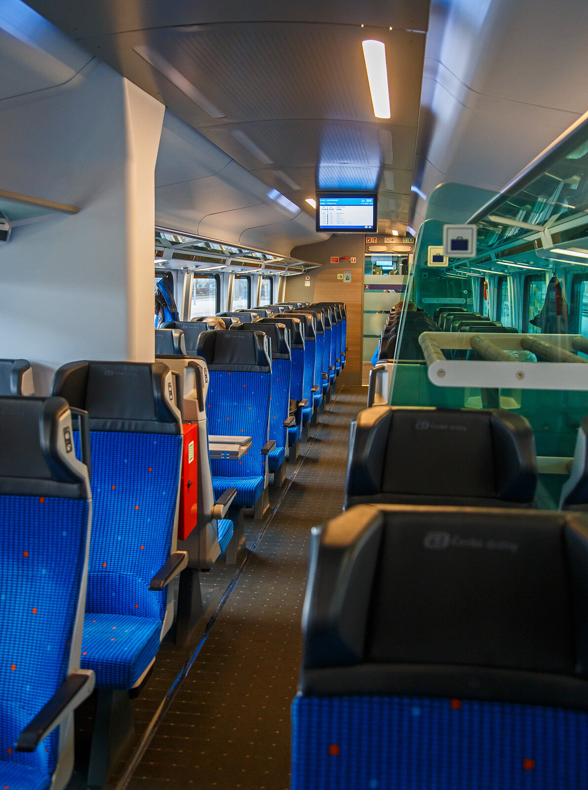 Innenraum von einem  2.Klasse ČD InterJet Gro�raumwagen der Gattung Bmpz 895 (CZ- ČD 73 54 21-91060 bis 079) der ČD - Česk� dr�hy eingereiht als Wagen 368 in den R15 „Kru�nohor“ (Cheb - Karlovy Vary - Praha hl.n.), am 17.04.2023 im Bahnhof Cheb (Eger).

Die ČD bestellte 50 Reisezugwagen, in Form von 10 f�nfteiligen Wageneinheiten die im regul�ren Betrieb fest verbunden sind. Diese UIC-Z-Wagen wurden zwischen 2019 und 2021von Siemens Wien (Fertigung) und �KODA VAGONKA Ostrava (Montage) gebaut. Die Einheiten haben keinen Steuerwagen, sie sind an beiden Enden mit Schraubkupplungen  und Puffern (Standard Zug-Sto�-Einrichtung) ausgestattet. Man geht davon aus, dass sie auf den Strecken Prag – Pilsen – Cheb und Prag – �st� nad Labem – Chomutov – Cheb eingesetzt werden. Eine Einheit besteht aus einem 1.-Klasse-Wagen, einem 2.-Klasse-Wagen mit Platz f�r Rollstuhlfahrer und f�r Reisende mit Kindern, zwei 2.-Klasse-Wagen ohne Sonderausstattung und einem 2.-Klasse-Wagen mit Platz f�r den Fahrradtransport. 