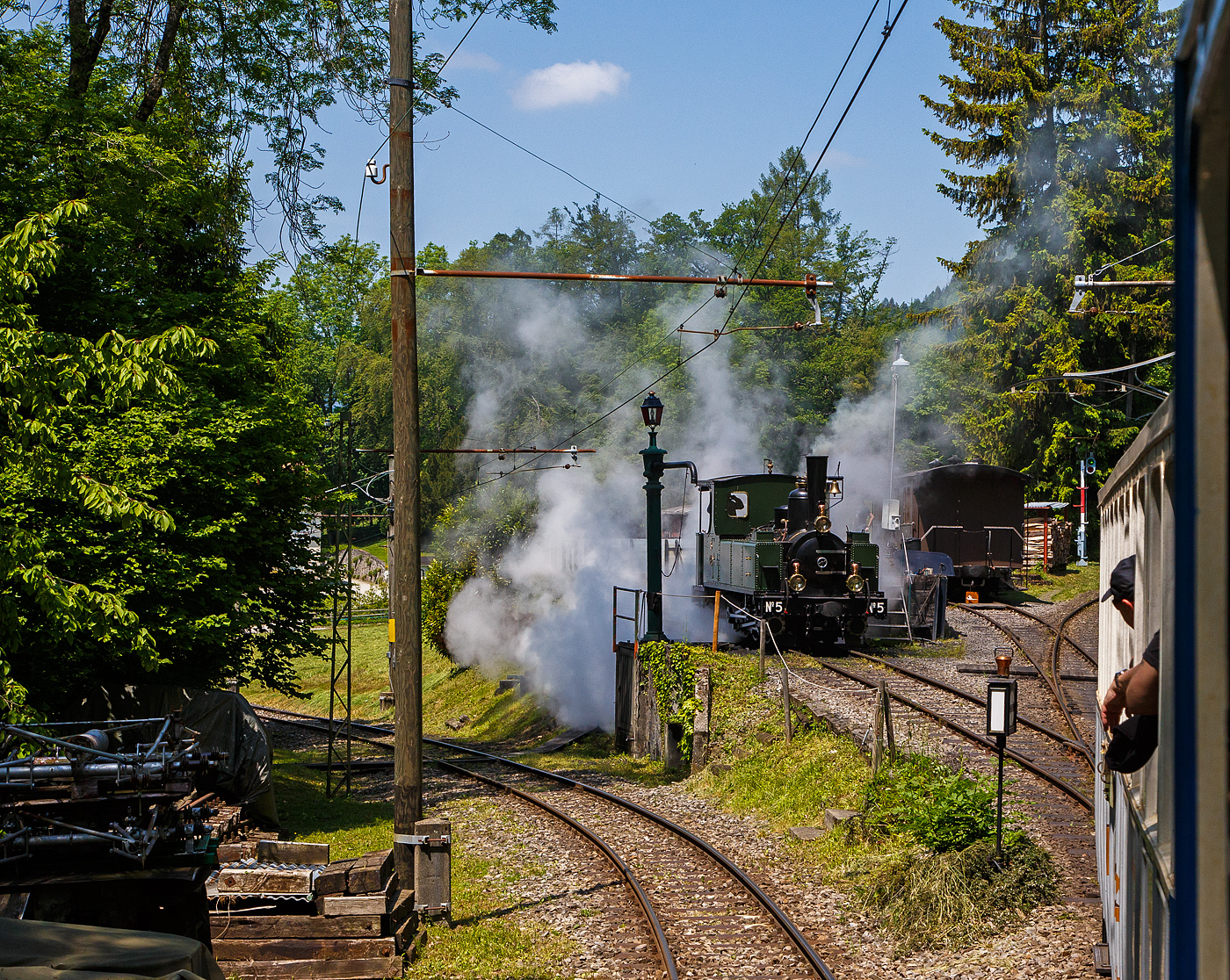 Museumsbahn-Romantik pur – Pfingsten 2023 (Samstag 27. bis Montag 29. Mai 2023) fand bei der Museumsbahn Blonay–Chamby das Schweizer Dampffestival 2023 / Festival suisse de la Vapeur 2023 statt.

Bei der Dampflok-Wartungsstelle der Museumsbahn Blonay–Chamby beim Museumsareal in Chaulin steht am 27.05. 2023 die G 3/3 LEB N° 5  Bercher  der Museumsbahn zum Kohlefassen. Links die Strecke 115 der MVR hinab nach Blonay, wir fahren mit dem ex MOB BCFe 4/4 11 rechts das Stichgleis zum Museum bzw. Depot hinauf.

Die ex LEB Nr. 5  Bercher  (Lausanne–Echallens–Bercher-Bahn) wurde 1890 von der Elsässische Maschinenbau-Gesellschaft Grafenstaden (später Société Alsacienne de Constructions Mécaniques) unter der Fabriknummer 4172 gebaut und an die Lausanne–Echallens–Bercher-Bahn geliefert. Die EMBG hatte auch zwei Jahre zuvor die baugleiche Nr. 2 geliefert. Die beiden dreiachsigen Tenderlokomotiven trugen die Hauptlast des Verkehrs, bis in den Jahren 1903 und 1905 zwei baugleichen Tenderlokomotiven, die G 3/3 6 „Gros-de-Vaud“ und G 3/3 7 „Talent „durch die Schweizerische Lokomotiv- und Maschinenfabrik (SLM) in Winterthur abgeliefert wurden. 

Von der YSteC konnte die LEB 1920/1921 die drei 1893 ebenfalls durch die EMBG gebauten Mallet-Lokomotiven G 2x2/2 Nr. 1 bis 3 gebraucht übernehmen. Nun waren die G 3/3 Nr. 2 und 5 nicht mehr gefragt. Während die G 3/3 2 „Échallens“ bereits 1929 verschrottet wurde (seit 1920 war sie bereits abgestellt), die G 3/3 Nr. 5  Bercher  hatte es da etwas besser, sie wurde 1934 an die Firma Energie de l’Ouest Suisse (EOS) für die Baustelle der Staumauer Grande-Dixence verkauf. Nach dem die Arbeiten 1935 erledigt sind geht sie bei der EOS außer Betrieb. Im Jahr 1939 verlässt die Schweiz und geht nach Vorarlberg in Österreich, zu einer Baufirma. Die Baufirma verschenkte 1967 die Lok und sie wurde, wie viele andere Dampflokomotiven zu dieser Zeit, auf einem Kinderspielplatz in der Stadt Feldkirch aufgestellt. Das Ausstellungsobjekt weckte die Aufmerksamkeit einiger Mitarbeiter der Museumsbahn Blonay–Chamby (BC), denen es gelang 1973 diese Lokomotive im Tausch gegen eine andere Lok zu erwerben.

Nach einer Aufarbeitung war die Lokomotive 1985 bis 2005 in Betrieb. Dann musste sie abgestellt werden. 2013/2014 wurde die Lokomotive ein zweites Mal durch die Museumseisenbahner aufgearbeitet. Seit dem Frühling 2015 ist die zweitälteste Schmalspur-Dampflokomotive der Schweiz, die älteste ist die G 3/4 1 „Rhätia  der Rhätischen Bahn (RhB), nach dem Abschluss der Revisionsarbeiten wieder in Betrieb.

TECHNISCHE DATEN der LEB G 3/3 N° 5  Bercher :
Baujahr: 1890
Spurweite: 1.000 mm
Achsformel: C
Länge über Puffer: 6.830 mm
Achsabstand: 1.800 mm (950mm / 850 mm)
Dienstgewicht: 20,4 t
Anzahl der Zylinder: 2
Zylindergröße: Ø 270 mm x 370 mm Kolbenhub
Treibraddurchmesser: 810 mm
Höchstgeschwindigkeit: 25 km/h
Stundenleistung: 150 PS
Kesselüberdruck: 12 bar
Kohlevorrat: 0,8 t
Wasservorrat: 2,2 m³

Die Lausanne–Echallens–Bercher-Bahn, abgekürzt LEB, französisch Chemin de fer Lausanne–Echallens–Bercher, ist eine meterspurige Privatbahn. Die knapp 24 Kilometer lange Strecke führt vom Stadtzentrum von Lausanne (Flon) durch die nördlichen Vororte und weiter nach Echallens und Bercher im Gros de Vaud, dem Waadtländer Hinterland. Die LEB ist eine moderne Vorortbahn, die in Lausanne teilweise unterirdisch verkehrt. Die Züge fahren alle 30 Minuten (zwischen Echallens und Bercher gibt es einige wenige Taktlücken am Vormittag). Werktags wird ein Viertelstundentakt bis Cheseaux angeboten. Von Montag bis Freitag verkehren in Lastrichtung einige beschleunigte Hauptverkehrszüge.