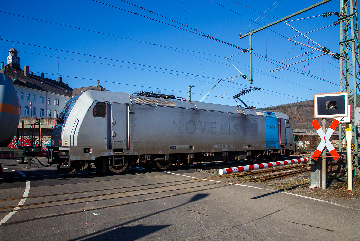 Nun sind die Schranken am Bü 343 geschlossen und sie hat Hp 1 oder 2...
Die 185 696-2 „Marie-Chanthou“ (91 80 6185 696-2 D-Rpool) der Railpool fährt am 14.02.2023 mit einem Druckgas-Kesselwagenzug über die Siegstrecke (KBS 460), durch Niederschelderhütte in Richtung Siegen.

Die TRAXX F140 AC2 wurde 2010 von Bombardier in Kassel unter der Fabriknummer 34722 gebaut und an die Railpool geliefert. Die Lok ist für Deutschland und Österreich zugelassen. Die ehemaligen Zulassungen für Schweden und Norwegen sind nun durchgestrichen.