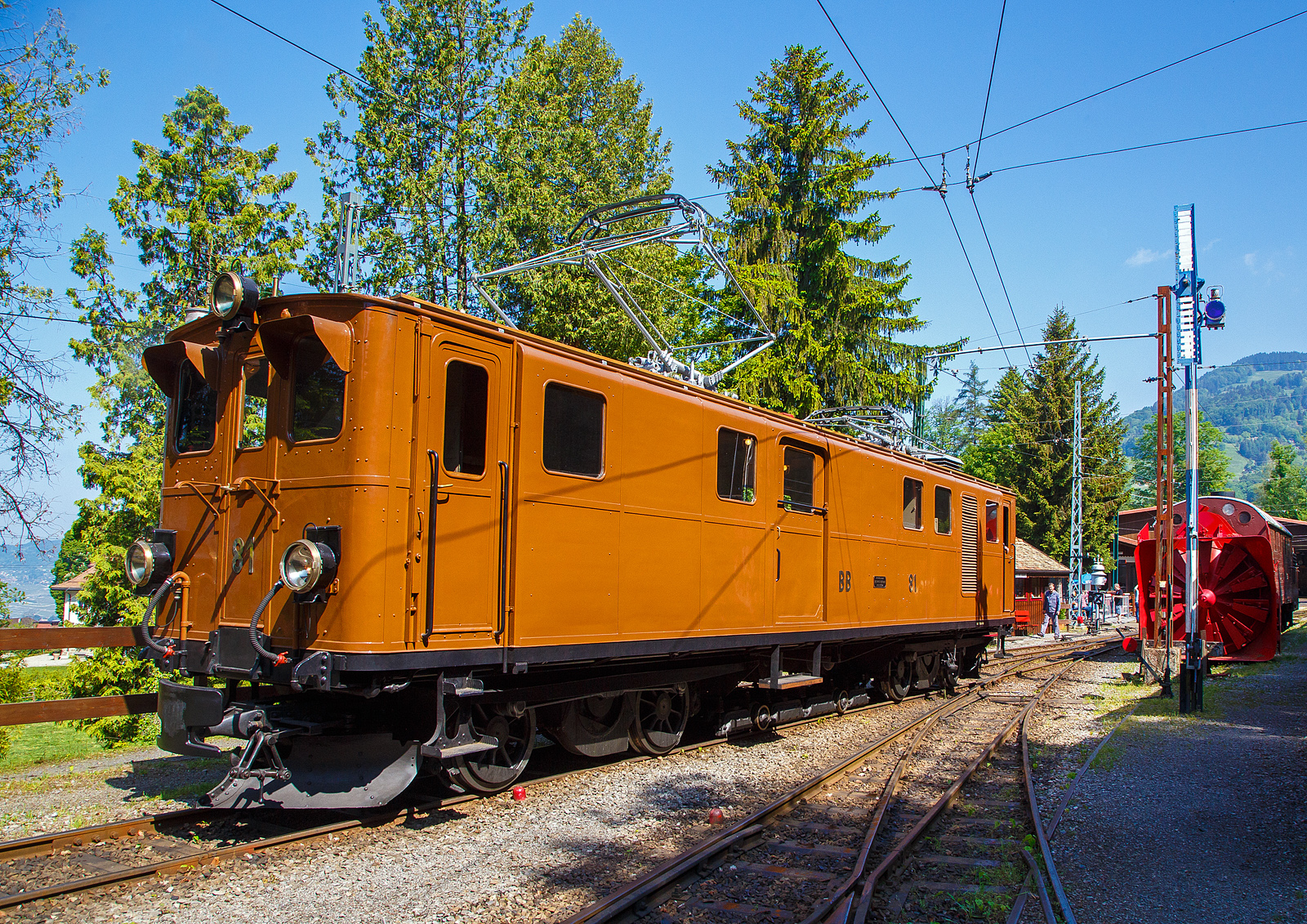 Pfingsten 2023 (Samstag 27. bis Montag 29. Mai 2023) fand bei der Museumsbahn Blonay–Chamby das Schweizer Dampffestival 2023 / Festival suisse de la Vapeur 2023 statt.

Die grandiose ehemalige Berninabahn RhB Ge 4/4 81 der Museumsbahn Blonay–Chamby, ex RhB Ge 4/4 181, ex BB Ge 4/4 81, ex BB Ge 6/6 81, am 27. Mai 2023 beim Umsetzen auf dem Museums-Areal der (BC) in Chaulin. Eigentlich da die Lokomotive ein kleines Gep�ckabteil und sechs Achsen besitzt, m�sste sie als Triebwagen De 4/6 bzw. Fe 4/6 (ex Fe 6/8) klassifiziert sein, aber die Berninabahn und sp�ter die RhB wollten sie als Lokomotive und nicht als Triebwagen klassifizieren.

Rechts ein weiteres Relikt der Berninabahn, die Selbstfahrende Dampfschneeschleuder R 1052 (ex BB R 1052 (Berninabahn), ex RhB R 14, ex RhB Xrot d 9214), der Museumsbahn Blonay-Chamby. Dieses Fahrzeug wie auch das heute noch bei der RhB betriebsf�hige Schwesterfahrzeug Xrot d 9213 (ex BB R 1051) sind dampfgetriebene Schneeschleudern mit eigenem Antrieb die f�r die Berninabahn (BB) gebaut wurden, die seit 1944 zur Rh�tischen Bahn geh�rt. Im Gegensatz zu den bisher gebauten Fahrzeugen, auch der zwei Dampfschleudern der RhB-Stammstrecke, handelt es sich bei den beiden Bernina-Schleudern um selbstfahrende Fahrzeuge. Die Berninabahn entschied sich hierzu, weil in den engen Kurven mit nicht gen�gend hoher Kraft geschoben werden konnte und die Bahn selbst keine Fahrdraht-unabh�ngigen Triebfahrzeuge besa�. Die Schleudern wurden dennoch normalerweise mit Schiebetriebfahrzeugen eingesetzt, damit die gesamte Kesselleistung f�r die Dampfmaschine des Schleuderrades zur Verf�gung stand.

Die Ge 4/4 81war urspr�nglich eine sechsachsige Elektrolokomotive (Ge 6/6) der ehemaligen Berninabahn (BB), welche 1943 in der Rh�tischen Bahn (RhB) aufging. Als Einzelst�ck wurde sie von der Schweizerischen Lokomotivfabrik in Winterthur (SLM) mit elektrischer Ausr�stung von Brown, Boveri & Cie. (BBC) hergestellt und 1916 abgeliefert. Als schmalspurige Elektrolokomotive mit sechs angetriebenen Achsen erhielt sie die Bauartbezeichnung Ge 6/6 und die Betriebsnummer 81, bereits 1929 wurde sie bei der SLM in Winterthur zur BB Ge 4/4 81 umgebaut.

Die damals rasche Verkehrszunahme verlangte nach einer eigenen Lokomotive f�r den schweren Verkehr. Mit einem Gewicht von 45 Tonnen, verteilt auf urspr�nglich sechs Antriebsachsen und zwei kleine Achsen f�r den Hilfsrahmen des Bremsgestells mit der elektromagnetischen Schienenbremse, und vier Fahrmotoren galt sie damals als st�rkste meterspurige Lokomotive Europas. Je zwei Motoren waren in einem Drehgestellrahmen fest verschraubt, die Kraft�bertragung erfolgte von der Motorwelle zun�chst auf eine Vorgelegewelle. Die beiden Vorgelegewellen und die mittlere Triebachse jedes Drehgestells waren mit einem Dreiecksrahmen verbunden. Die �u�eren Achsen wurden mittels Kuppelstangen angetrieben. Diese Anordnung bew�hrte sich nicht. Es ist �berliefert, dass eine Dreieckskuppelstange in voller Fahrt nach Bruch der Kurbeln durch das Dach geschleudert wurde.

Umbau zur Ge 4/4 81:
1929 wurde die Lok von der Achsfolge C’C’ auf die Achsfolge B’B’, beim Hersteller SLM in Winterthur, umgebaut. Durch den Umbau sollte die Leistung der Lok f�r geplante Express-Z�ge erh�ht werden. Die mittlere Achse jedes Drehgestells wurde durch eine Blindwelle ersetzt. Die Kraft�bertragung von den Motoren her erfolgt neu durch ein Getriebe. Die Triebachsen werden durch Schlitzkuppelstangen angetrieben. Beim Umbau wurde die Lok auf die bevorstehende Spannungserh�hung von 750 Volt auf 1000 Volt vorbereitet. Dadurch konnte die Leistung von 960 PS auf 1040 PS gesteigert werden. Die zul�ssige H�chstgeschwindigkeit wurde von 50 km/h auf 45 km/h gesenkt.

Als Besonderheit besitzt die Lokomotive einen mit zwei Achsen ausger�steten Hilfsrahmen f�r die aus der Fahrleitung gespeiste elektromagnetische Schienenbremse. Infolge dieses Hilfsrahmens h�tte die Lokomotive korrekterweise die Achsfolge B’2’B’, urspr�nglich C’2’C’. Die Bauartbezeichnung einschlie�lich des Bremsgestells w�rde Ge 4/6 (beziehungsweise fr�her Ge 6/8) lauten, unter Ber�cksichtigung des Gep�ckabteils De 4/6 (fr�her Fe 4/6 beziehungsweise Fe 6/8).

Bei der Rh B - Rh�tischen Bahn erhielt die Lokomotive 1961 die Betriebsnummer 181. 1970 wurde sie ausgemustert und kam zur Museumsbahn Blonay–Chamby (BC), wo sie anf�nglich regelm��ig eingesetzt wurde. Ab 1990 verhinderte ein Schaden an der elektrischen Ausr�stung die weitere Nutzung. Erst 2008 konnte die Lokomotive mit Hilfe eines Sponsors so weit aufgearbeitet werden, dass sie seither wieder eingesetzt werden kann.

Am 23. August 2021 wurde die Lok auf der Stra�e nach Landquart �berf�hrt, damit sie Anfang Oktober bei Sonderfahrten auf der Berninabahn eingesetzt werden konnte. Nachdem die BC und der Club 1889, der in Samedan historische Fahrzeuge der RhB erh�lt, die Lokomotive f�r den Einsatz am Bernina angepasst haben, zog die Lokomotive im Februar 2022 aus eigener Kraft einen Extrazug von St. Moritz zur Station Alp Gr�m (2.091 m.�.M.). In Folge wurde die Maschine f�r weitere Sonderfahrten auf ihrer ehemaligen Stammstrecke eingesetzt und kehrte erst im Oktober 2022 wieder zur Museumsbahn BC zur�ck.

TECHNISCHE DATEN  der Ge 4/4 81 (Ge 4/6):
Betriebsnummern: BB 81 / RhB 81 / RhB 181
Gebaute Anzahl: 1 (Eizelst�ck)
Hersteller mecha. Teil: Schweizerischen Lokomotivfabrik in Winterthur (SLM) 
Elektrischer Ausr�stung:  Brown, Boveri & Cie., M�nchenstein (BBC)
Inbetriebsetzung: 1916  (1929 Umbau von der Ge 6/6 zur Ge 4/4)
Spurweite: 1.000 mm (Meterspur)
Achsanordnung: B’B’, urspr�nglich C’C’
L�nge �ber Puffer: 13.900 mm
H�he �ber S.o.K.: 3.840 mm (abgesenkter Stromabnehmer) / 6.250 mm gehoben 
Drehzapfenabstand: 7.560 mm
Achsabstand im Drehgestell: 2.100 mm (Achse/Motor/Achse 1.150 / 950 mm)
Treibraddurchmesser: 855 mm (neu)
Achsabstand im Bremswagen: 1.360 mm
Laufraddurchmesser im Bremsgestell: 280 mm (neu)
Dienstgewicht: 46,0 t
H�chstgeschwindigkeit: 45km/h (anf�nglich 50 km/h)
Dauerleistung: 708 kW (4 x 177 kW) / 962 PS (urspr. 455 kW / 620 PS) 
Anfahrzugkraft: 14.500 kg
Getriebe�bersetzung: 1:4.28
Stromsystem: 900 V  DC (Gleichstrom)
Strom�bertragung: 2 Stromabnehmer
Anzahl der Fahrmotoren: 4
Antrieb: elektrisch
Bremse: Vakuumbremse, elektrische Widerstandsbremse, Magnetschienenbremsen