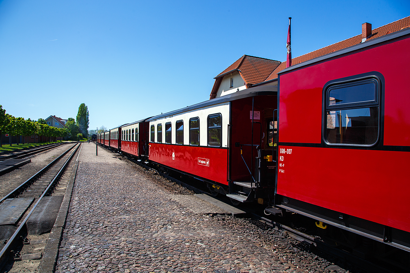 Schmalspuriger (900 mm) vierachsige 2.Klasse Personenwagen mit Traglastenabteil, offenen Plattformen und Holzdach, MBB 990-303 (ex DR 990-303), der Gattung KB4i, Mecklenburgische B�derbahn Molli GmbH & Co. (Molli), hier am 15 Mai 2022 im Bahnhof K�hlungsborn-West im Zugverband.

Der Wagen wurde 1925 von der Waggonfabrik Wismar f�r die Deutsche Reichsbahn Gesellschaft (DRG) gebaut und ist seitdem bei der Mecklenburgische B�derbahn im Einsatz, bereits 1938 wurde er einseitig als Traglastenwagen (f�r Kinderwagen etc.) hergerichtet. Im Februar 1981 wurde er rekonstruiert. Im Fuhrpark des Molli befinden sich insgesamt 19 Personenwagen.

TECHNISCHE DATEN:
Spurweite: 900 mm
Anzahl der Achsen: 4
L�nge �ber Puffer: 12.000 mm
Drehzapfenabstand: 6.500 mm
Eigengewicht: 15 t
Sitzpl�tze: 29 (in der 2. Klasse)
Bremse: KE-P 
