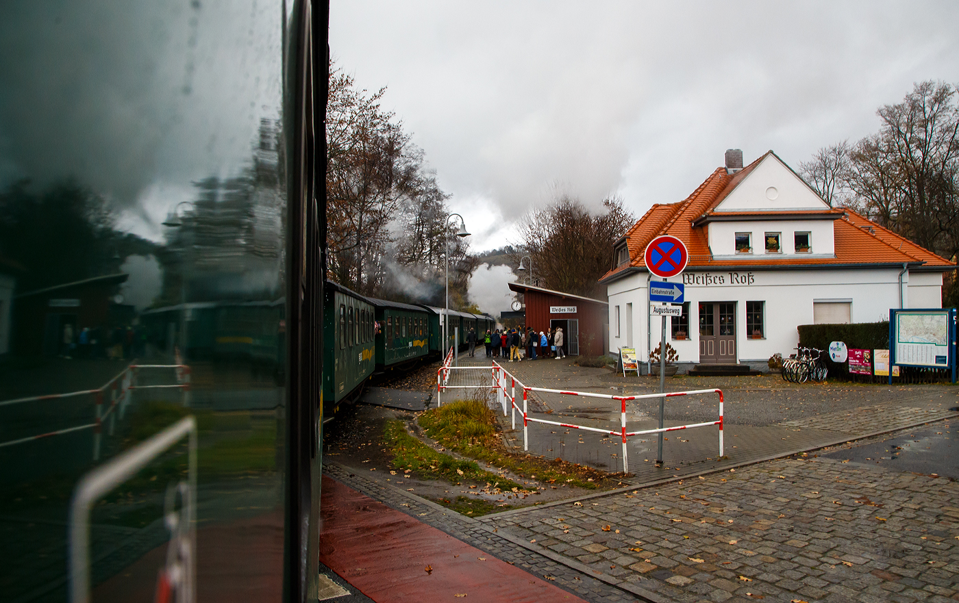 Unterwegs mit dem „Lößnitzdackel“  bzw. mit der Lößnitzgrundbahn der SDG - Sächsische Dampfeisenbahngesellschaft mbH, erreicht unser Dampfzug, gezogen von der sächsischen VII K (Altbau) 99 1761-6, nun am 07.12.2022 den Haltepunkt Weißes Roß (bei km 1,6), wir im letzten Wagen befinden uns noch am Bahnübergang Bü 1,5 - Meißner Straße in Radebeul.

Die Schmalspurbahn Radebeul Ost - Moritzburg - Radeburg ist eine sächsische Schmalspurbahn in der Spurweite von 750 mm außerhalb der sächsischen Landeshauptstadt Dresden. Für die Strecke wird heute auch die 1998 vergebene Marketingbezeichnung Lößnitzgrundbahn verwendet. Umgangssprachlich wird sie dagegen meist als Lößnitzdackel (kurz auch Dackel) oder früher Grundwurm bezeichnet.

Die in den Jahren 1911/1913 errichtete und heute denkmalgeschützte Bahnstation „Weißes Roß“ liegt nahe der Meißner Straße, wo sich die Schmalspurbahn Radebeul–Radeburg (Lößnitzgrundbahn – KBS 509) mit der Dresdner Straßenbahnlinie 4 kreuzt.

Die „Station“ besteht aus einem massiven, verputzten Bahnwärterhaus mit Fahrkartenschalter und Warteraum sowie einer nahebei gelegenen hölzernen Wartehalle. Das Bahnwärterhaus wurde 1913 durch die Königlich Sächsische Staatseisenbahnverwaltung errichtet. Es ist ein eingeschossiger, massiver Putzbau auf einem Bruchsteinsockel mit einem niedrigen Anbau, das Walmdach ist mit Ziegeln gedeckt, darin zwei Dachausbauten mit hohem Dreiecksgiebel. Die Wartehalle ist ein halboffenes, verbrettertes Fachwerk mit Pultdach.