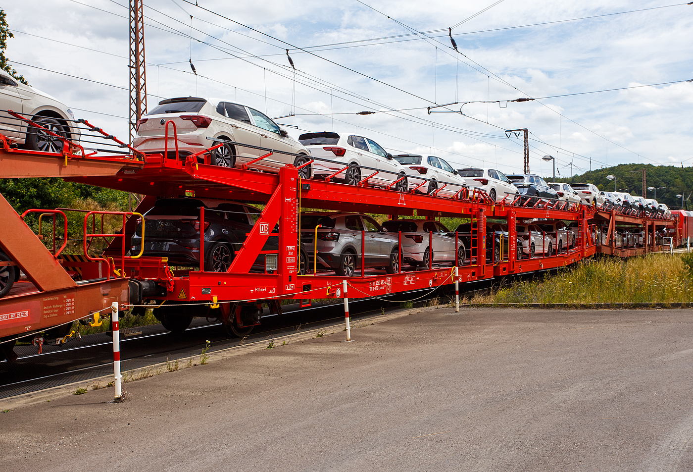 Vierachsiger (2 x zweiachsiger) Doppelstock-Autotransportwagen, 25 80 4363 493-4  D-ATG, der Gattung Laaers 560.2, der DB Cargo Logistics GmbH (ex DB Schenker ATG)  am 19 Juli  2024 im Zugverband bei der Zugdurchfahrt in Rudersdorf (Kreis Siegen), hier beladen mit VW PKW´s aus der „Stadt des KdF-Wagens bei Fallersleben“ (ab 1945 Wolfsburg).

Der Wagen wurde 201_ von der damaligen DB Waggonbau Niesky GmbH gebaut.

Diese Waggons haben zwei Ladeebenen und sind für den europaweiten Transport geeignet. Sie werden für den internationalen Transport von PKWs, SUVs und Vans eingesetzt und bieten maximale Flexibilität durch eine stufenlos verstellbare obere Ladeebene. Aufgrund der hohen Lastgrenze (bis 34 t) ist der Transport von besonders schweren Fahrzeugen der genannten Typen möglich.

Damit sowohl ein typenreiner Transport als auch eine Mischverladung in den unterschiedlichen Lademaßen möglich ist, kann die obere Ladeebene hinsichtlich der Transportstellungen stufenlos eingestellt werden.

Durch die Entwicklung eines veränderten Ladungssicherungssystems wurde den Kundenanforderungen nach optimierten Transportmöglichkeiten für Fahrzeuge mit niedrigerer Bodenfreiheit Rechnung getragen.

TECHNISCHE DATEN:
Gattung: Laaers (Bauart 560.2)
Erstes Baujahr der Wagengattung: 2007
Spurweite: 1.435 mm
Anzahl der Achsen: 4 (2 x 2)
Länge über Puffer : 31.000 mm
Achsabstände: 10.000 mm / 5.160 mm / 10.000 mm
Laufraddurchmesser (neu): äußere 840 mm und mittlere 730 mm
Ladelänge : 30.070 mm (unten) / 30.550 mm (oben)
Ladelänge waagerechter Teil untere Ebene: 19.400 mm
Ladebreite : 2.950 (unten) / 2.750 mm (oben)
Höchstgeschwindigkeit: 100 km/h (120 km/h leer)
Eigengewicht: 30.500 kg
Max. Zuladung bei Lastgrenze S: 33,5 t (ab Streckenklasse B, bei A 32,0 t)
Max. Zuladung der Ladeebenen: unten und oben jeweils max. 18 t
Max. Gewicht je Pkw: 2.800 kg (Radlast max. 1 t)
Anzahl der Radvorleger: 64
Höhe Geländer oben: 600 mm
Kleinster befahrb. Gleisbogenhalbmesser: 75 m
Bremse: KE-GP-A (K)
Bremssohle: Jurid 816 M
Handbremse: Ja
Intern. Verwendungsfähigkeit: TEN-GE

Der große Unterschied zwischen den Laaers-Wagen der Bauart 560.2 (wie hier) und der Bauart 560.1 sind das Lastgrenzenraster (Max. Zuladung), zudem ist die Bauart 560.2 meist 500 kg leichter.