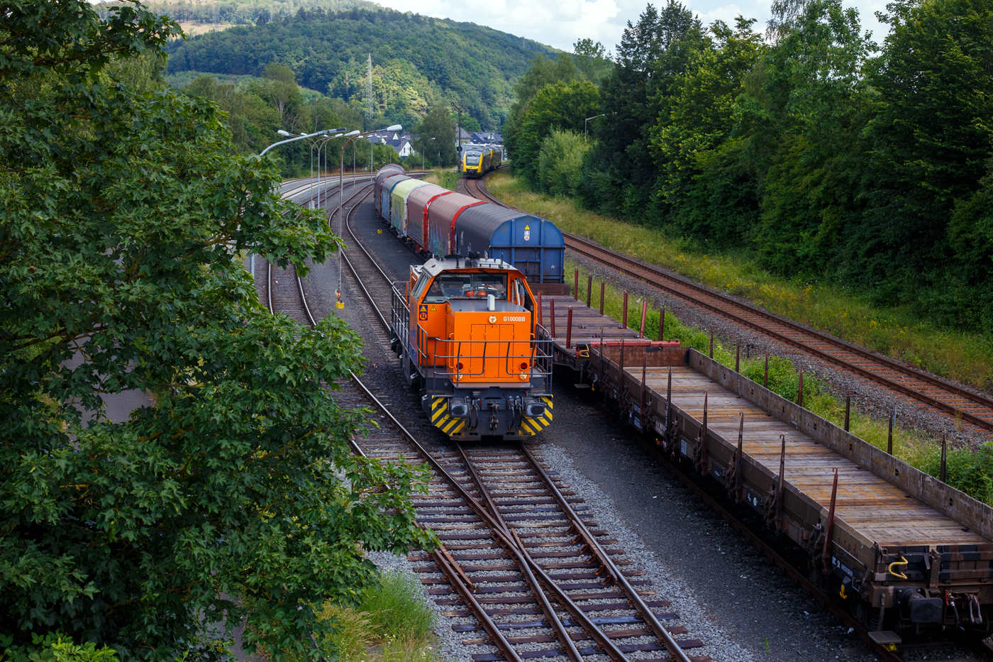 Während am 26 Juni 2024 die KSW 44 (92 80 1271 004-4 D-KSW) eine MaK G 1000 BB der KSW (Kreisbahn Siegen-Wittgenstein) auf dem KSW-Rangierbahnhof in Herdorf der Betriebsstätte FGE -Freien Grunder Eisenbahn (KSW NE447 / DB-Nr. 9275) rangiert, kommen auf der Hellertalbahn (KBS 462) zwei gekuppelte Alstom Coradia LINT  (41 und 27) der der HLB (Hessische Landesbahn) und erreichen bald, als RB 96 „Hellertalbahn“ (Haiger – Burbach – Neunkirchen – Herdorf – Betzdorf) / Umlauf HLB61780, den Bahnhof Herdorf.